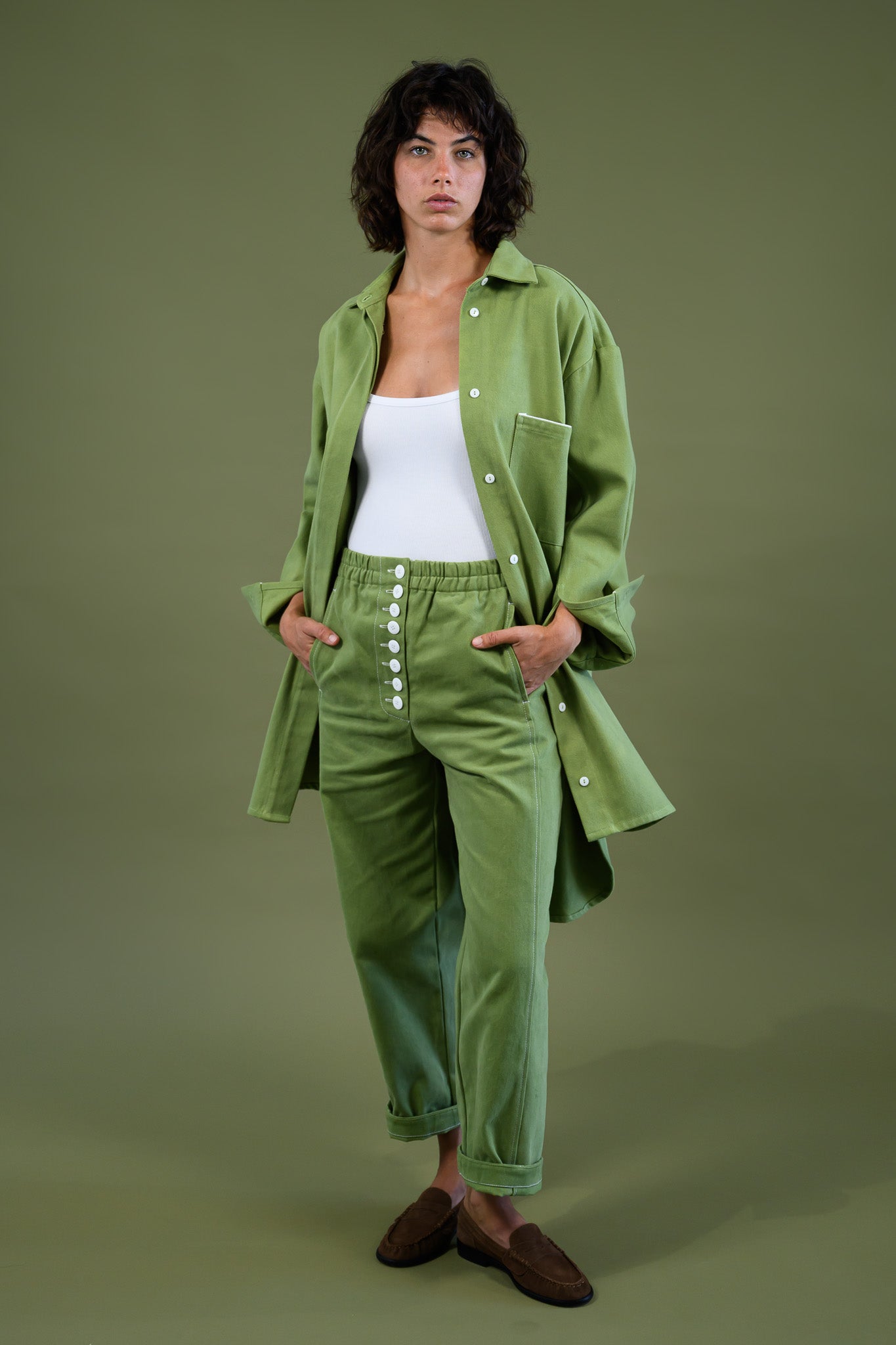 Womens field green canvas denim jacket relaxed fit shown in walking pose with matching pants and white top