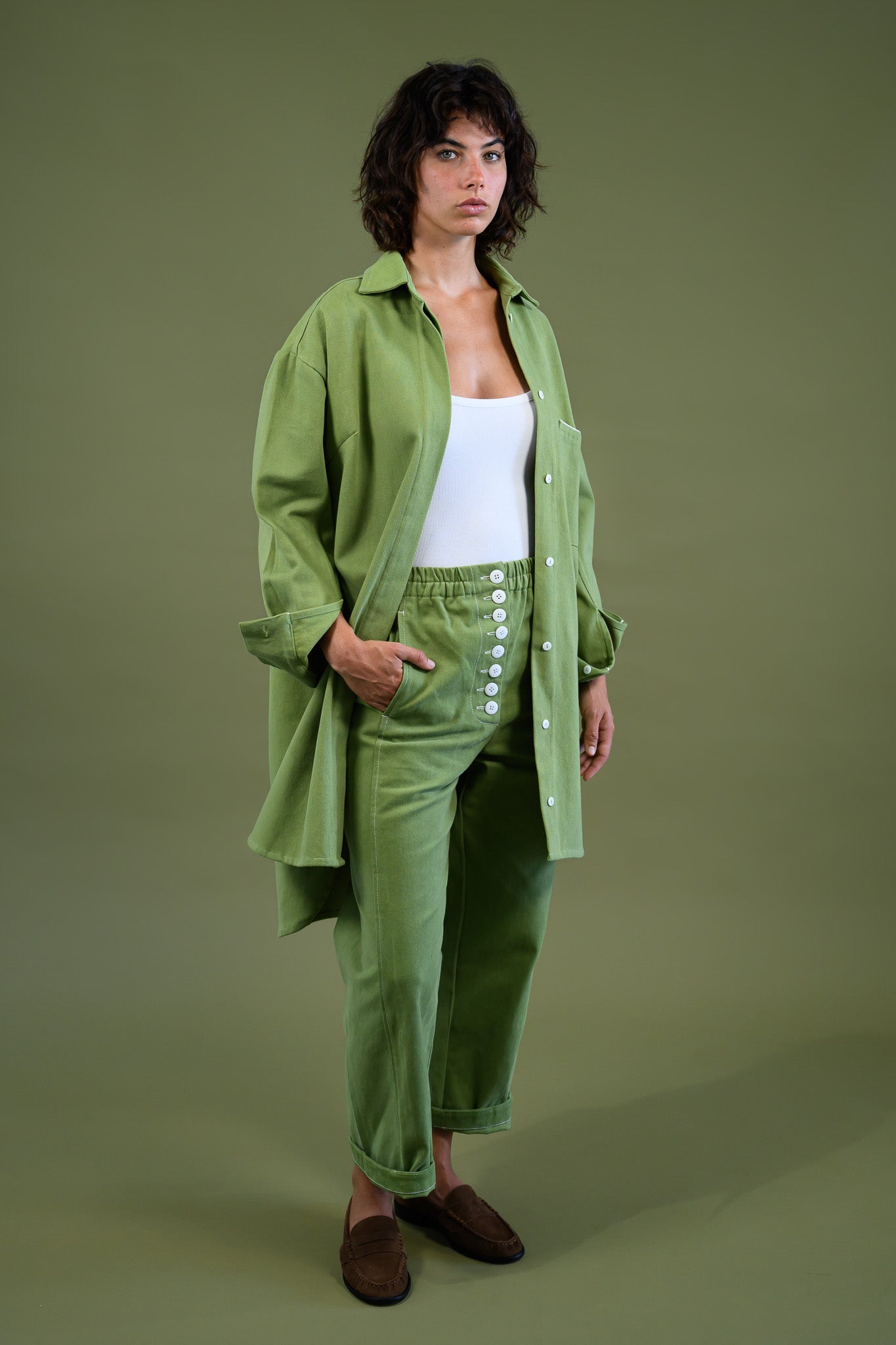 Womens field green canvas denim jacket walking three quarter view showing relaxed fit and movement