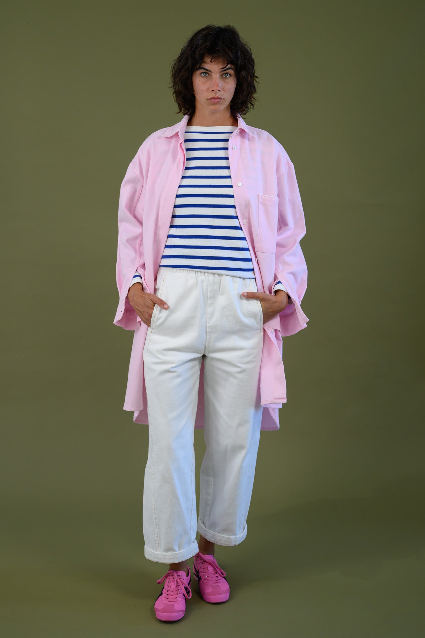 Womens pink canvas denim jacket styled with striped top and white pants full outfit front view