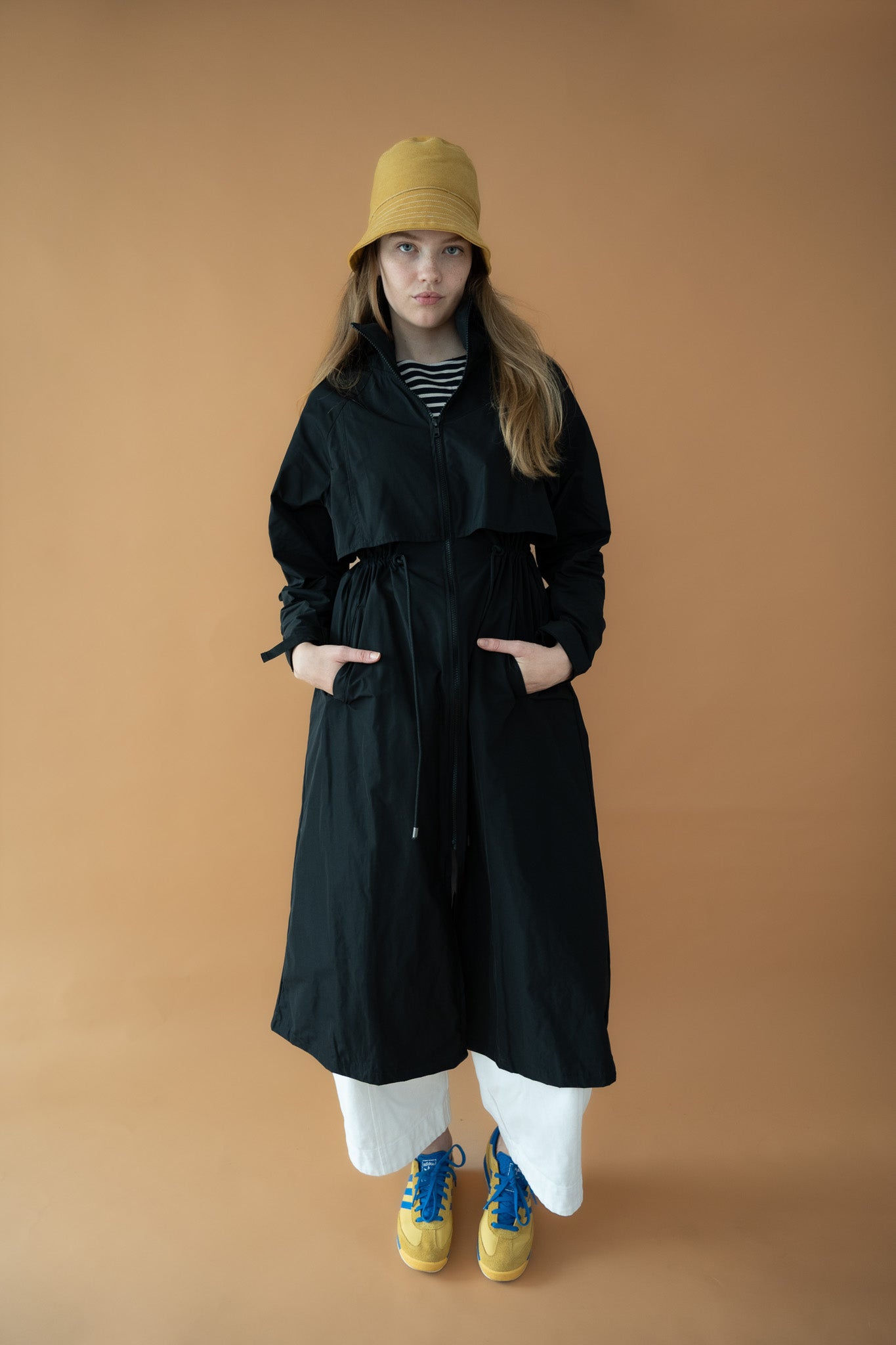 Full front view of the Cloud Breaker raincoat styled with yellow bucket hat and wide-leg white pants