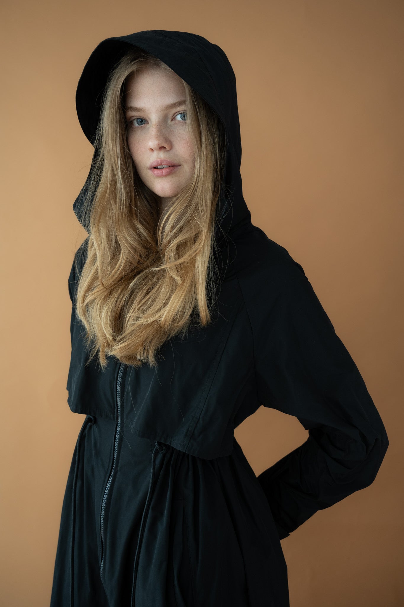 Model wearing Cloud Breaker raincoat with hood up, side angle view