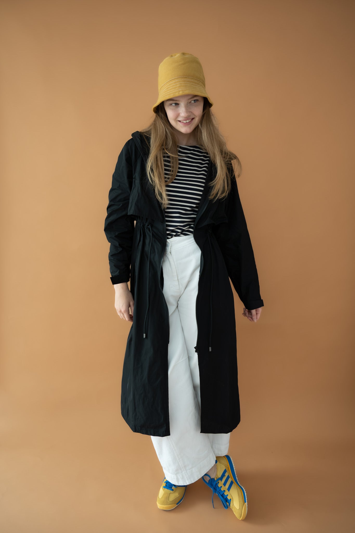 Cloud Breaker raincoat styled open over striped top and white pants with yellow sneakers