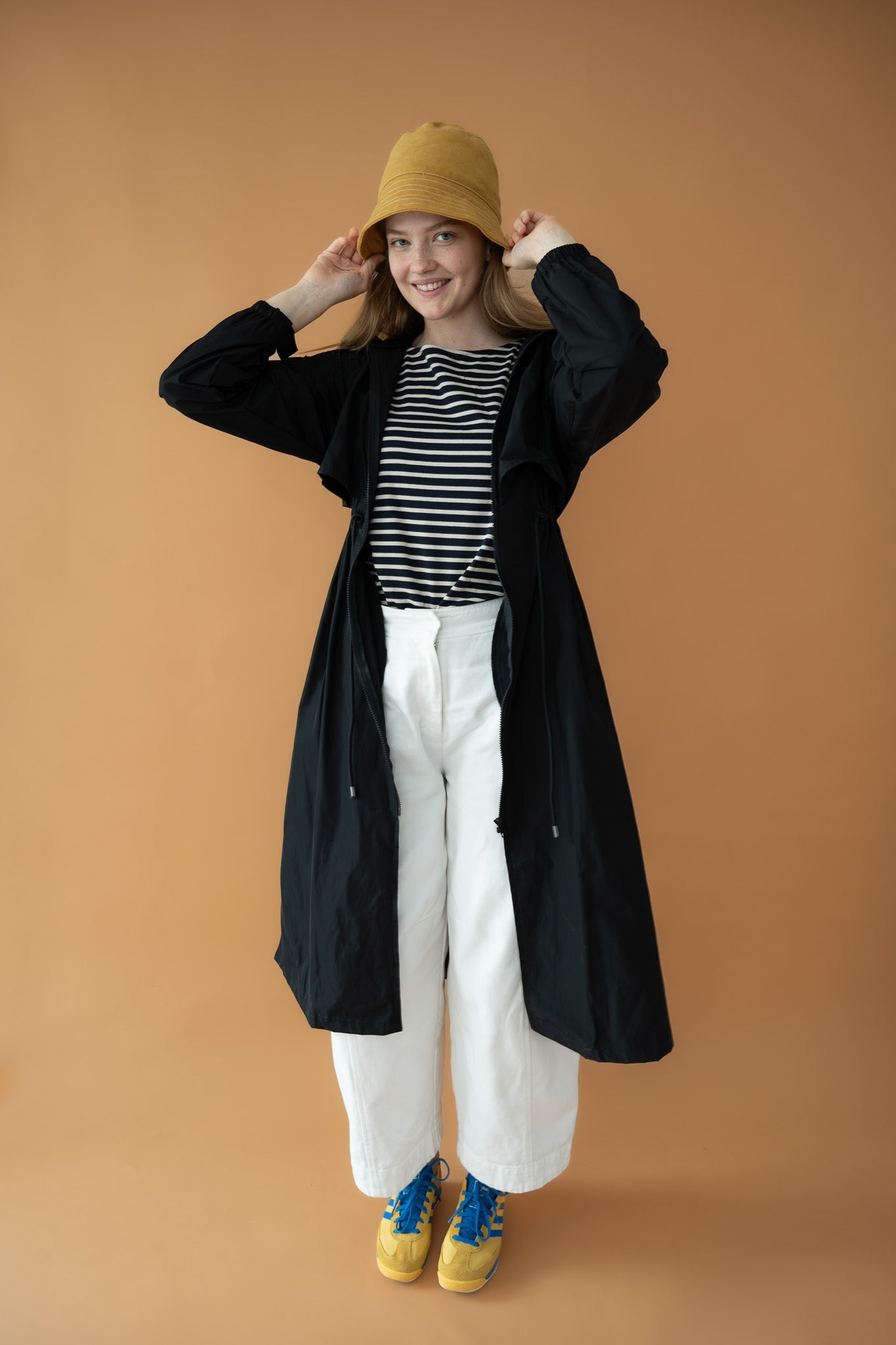 Model styling Cloud Breaker raincoat playfully open with striped top and yellow hat