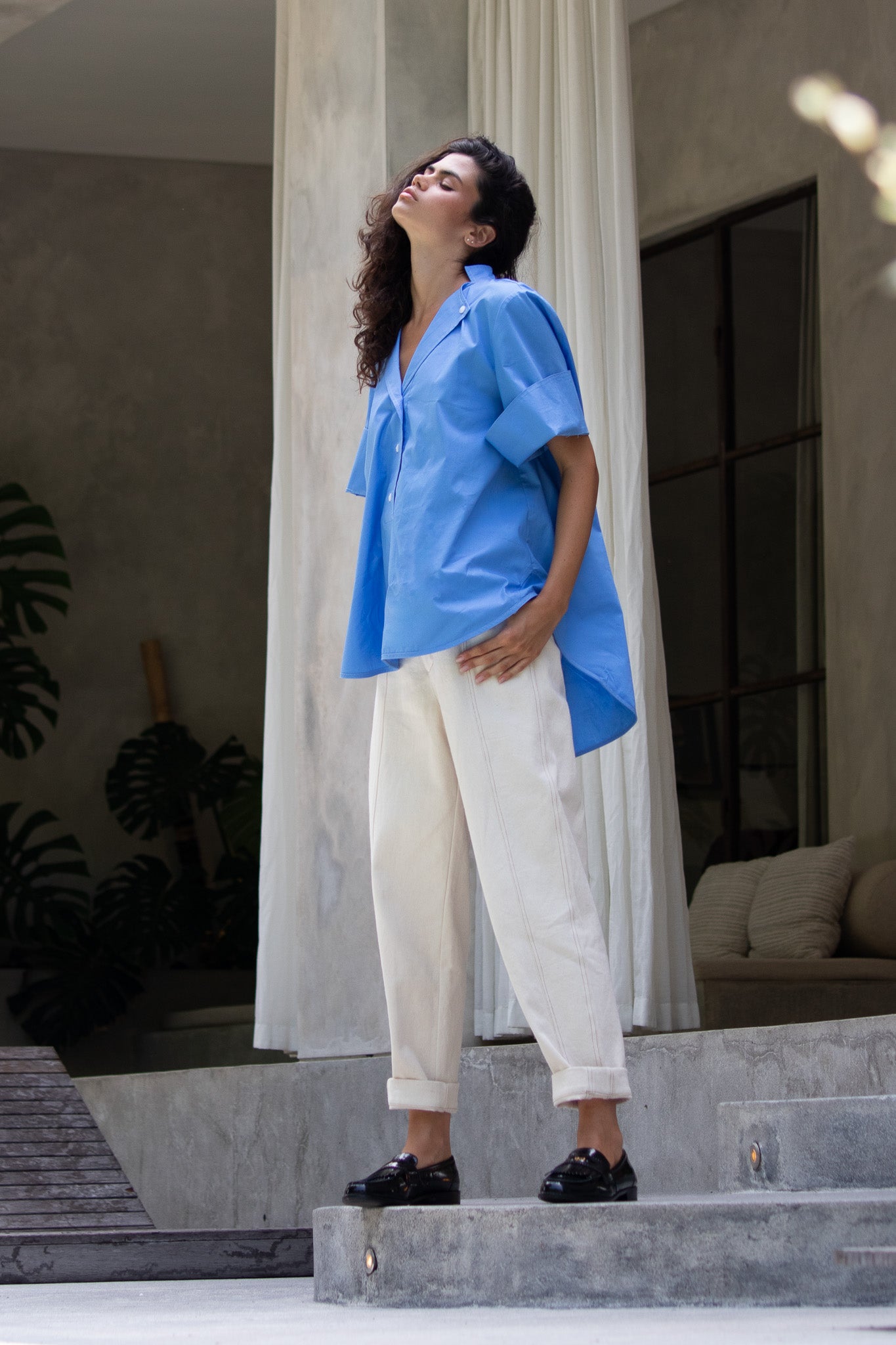 Calming image, model looking up wearing blue cotton poplin blouse