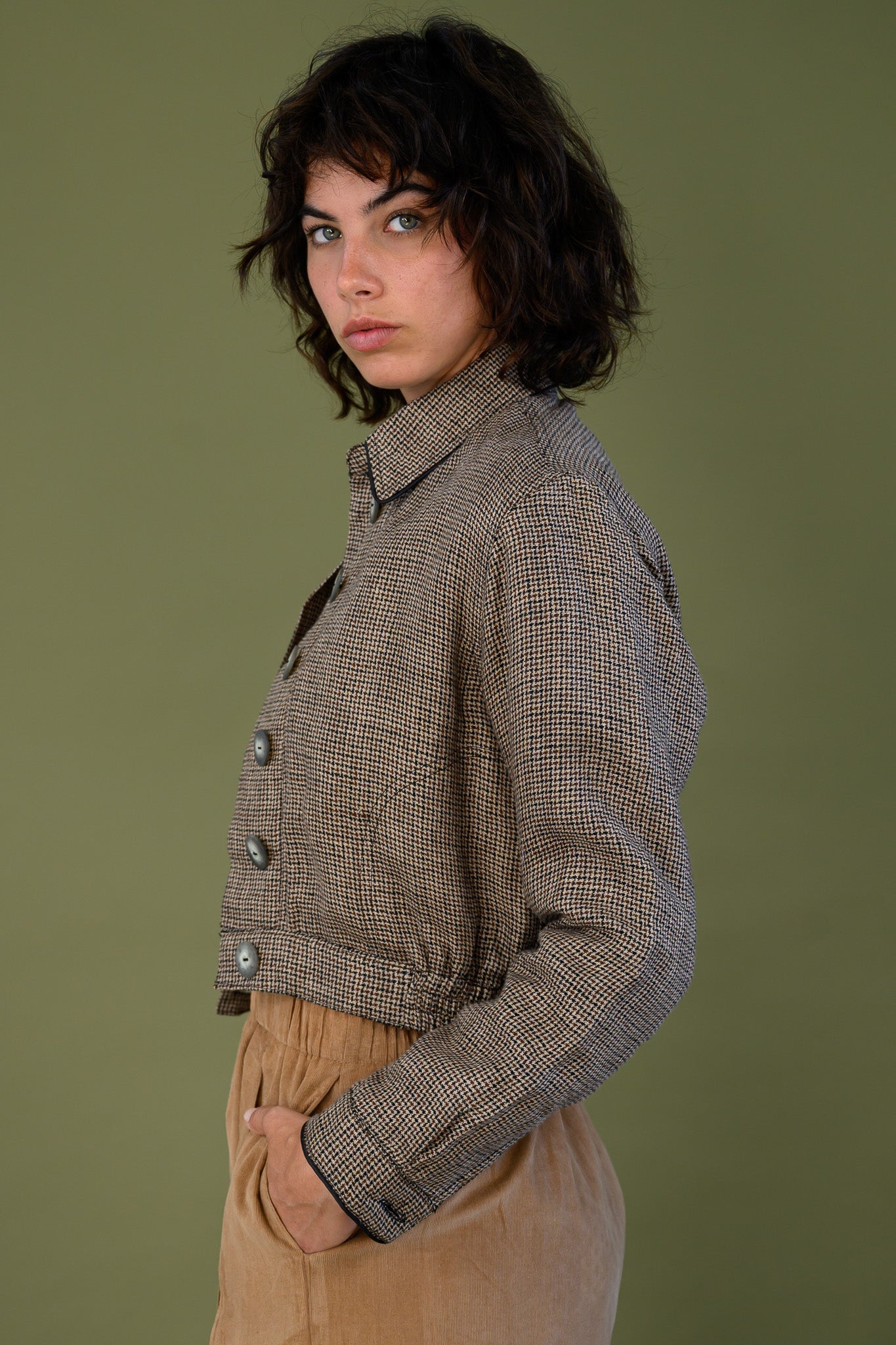 Side view of cropped check jacket showing button front and fitted waist