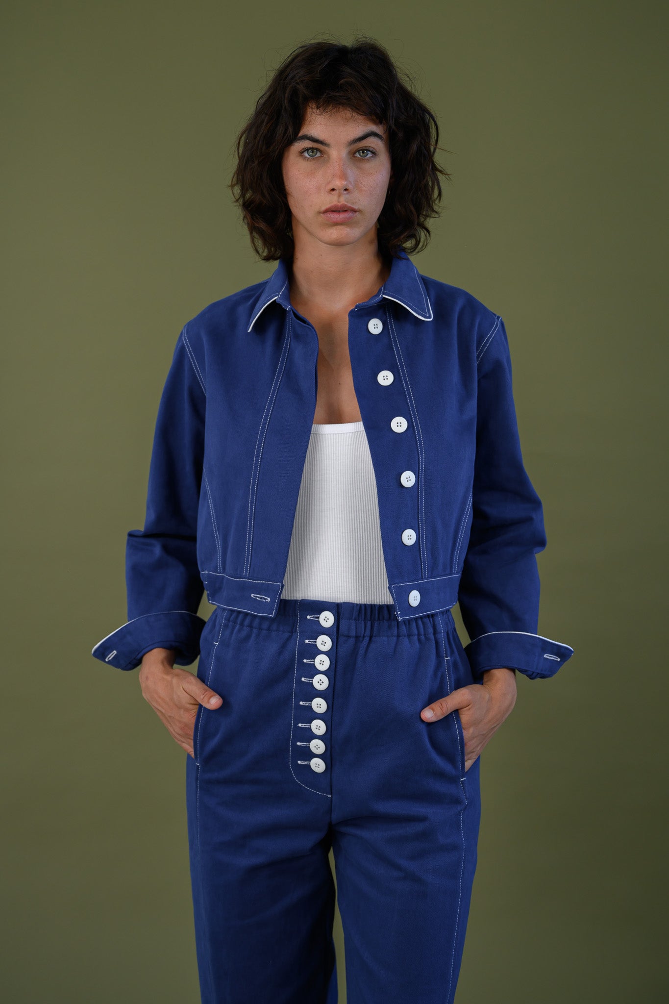 Front view of French navy cotton twill button pants styled with matching jacket highlighting button detail