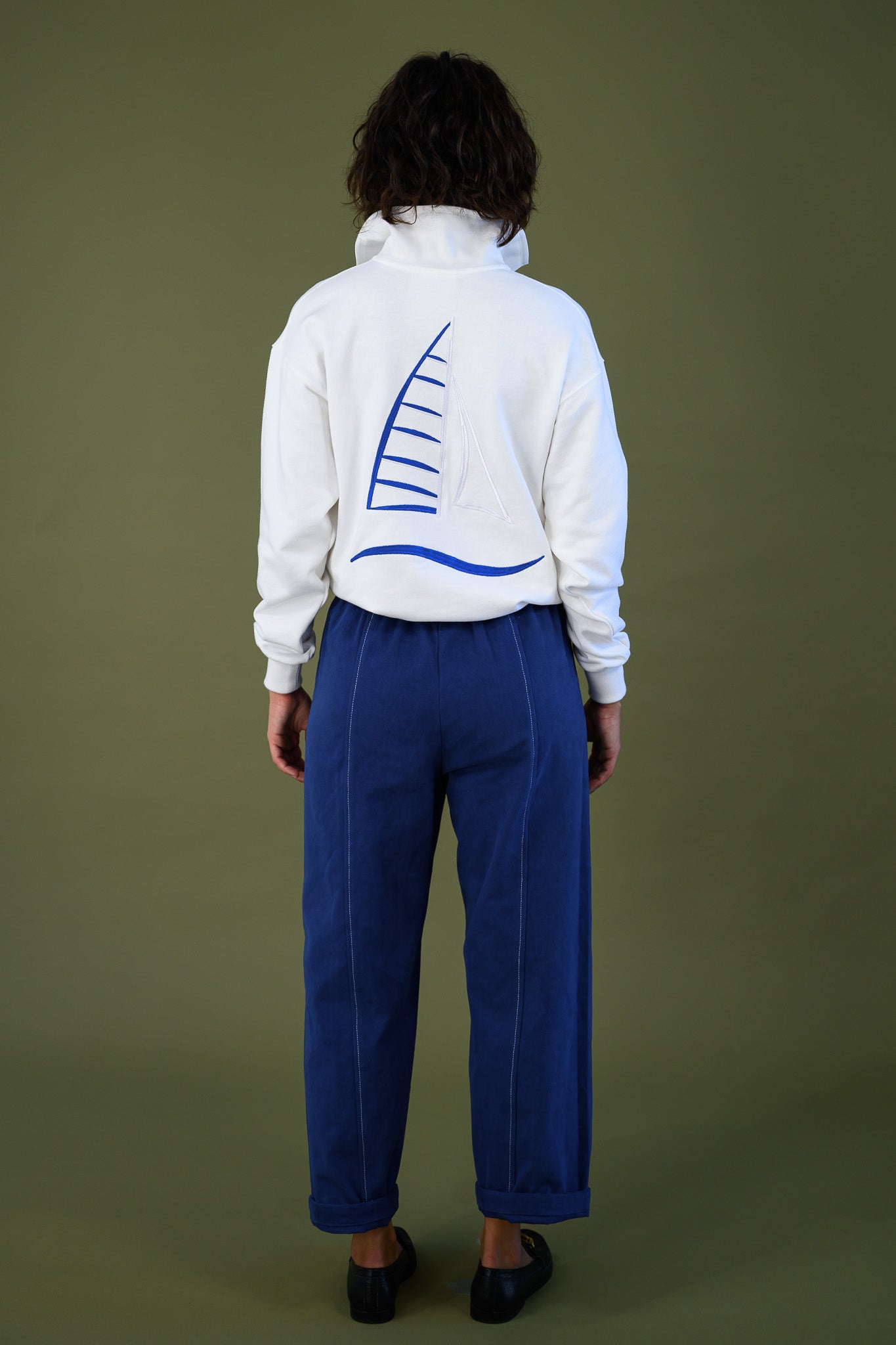 Back view of French navy cotton twill button pants showing relaxed fit styled with white sweatshirt