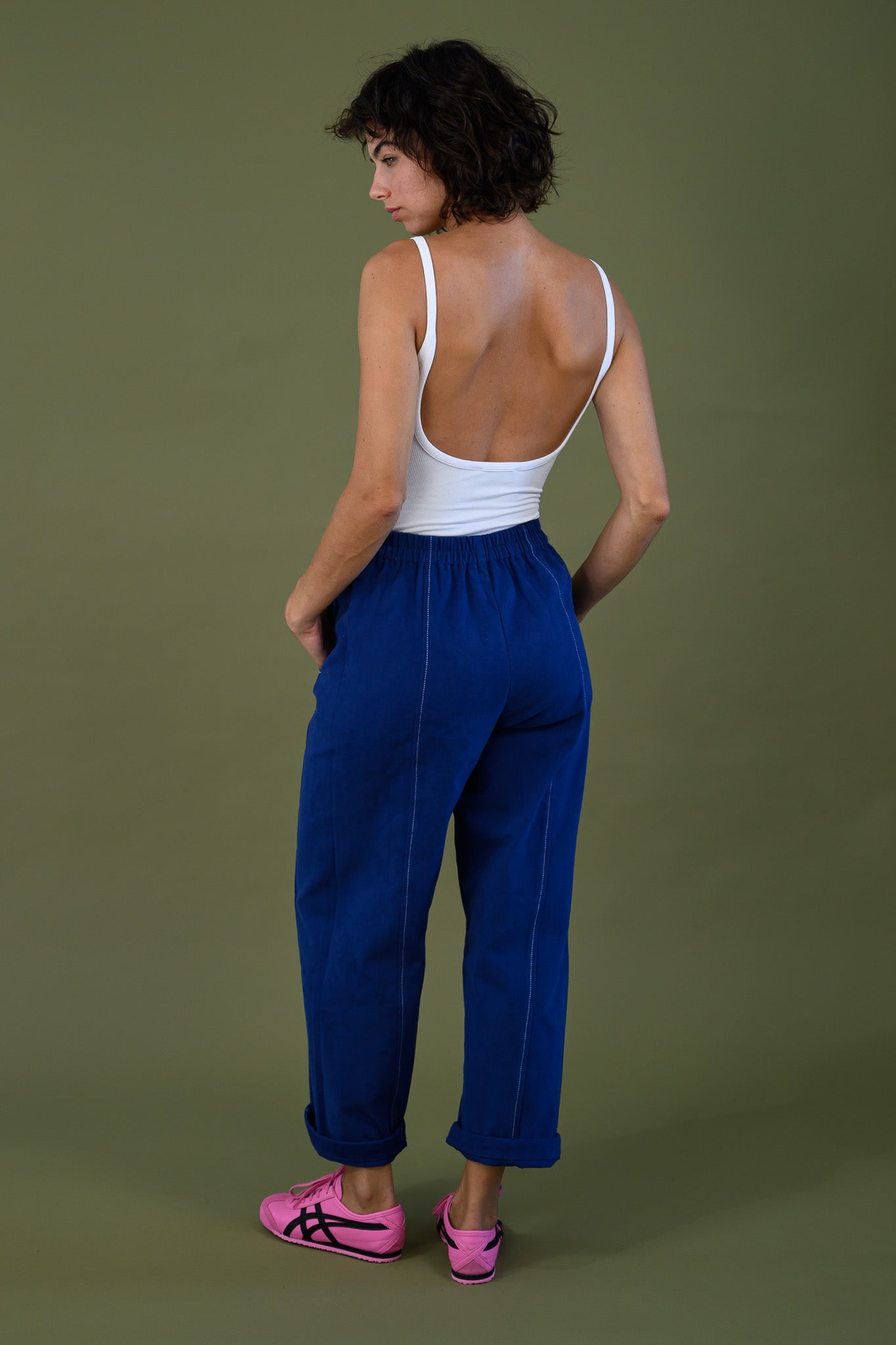 Back view of French navy cotton twill button pants showing tapered leg fit and elastic waist styled with white tank