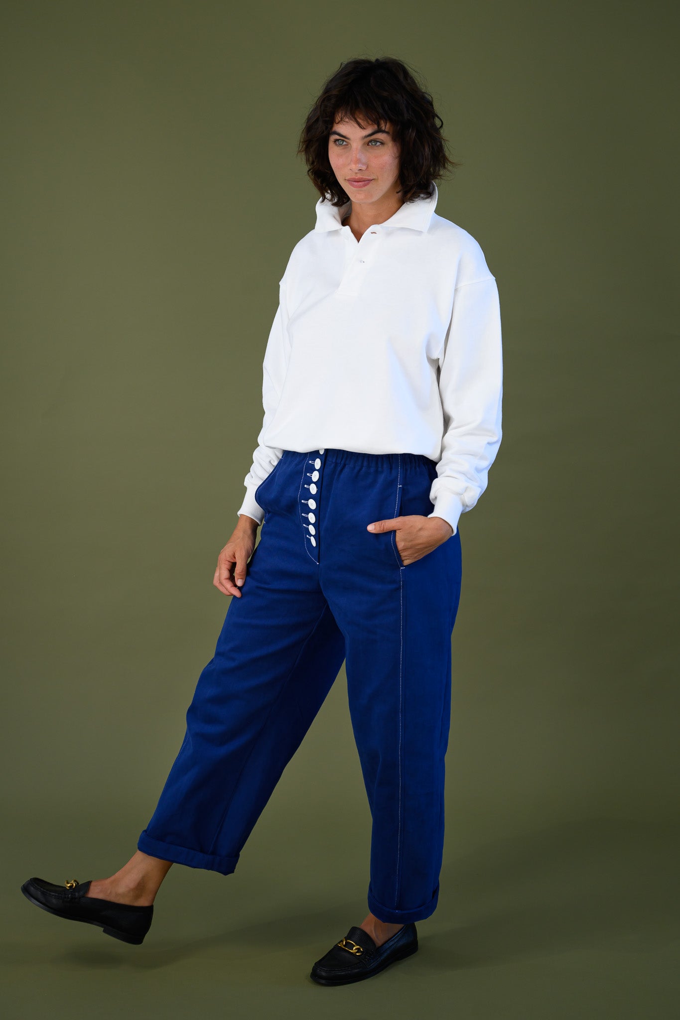 Angled front view of French navy cotton twill button pants showing barrel leg shape in movement styled with white sweatshirt