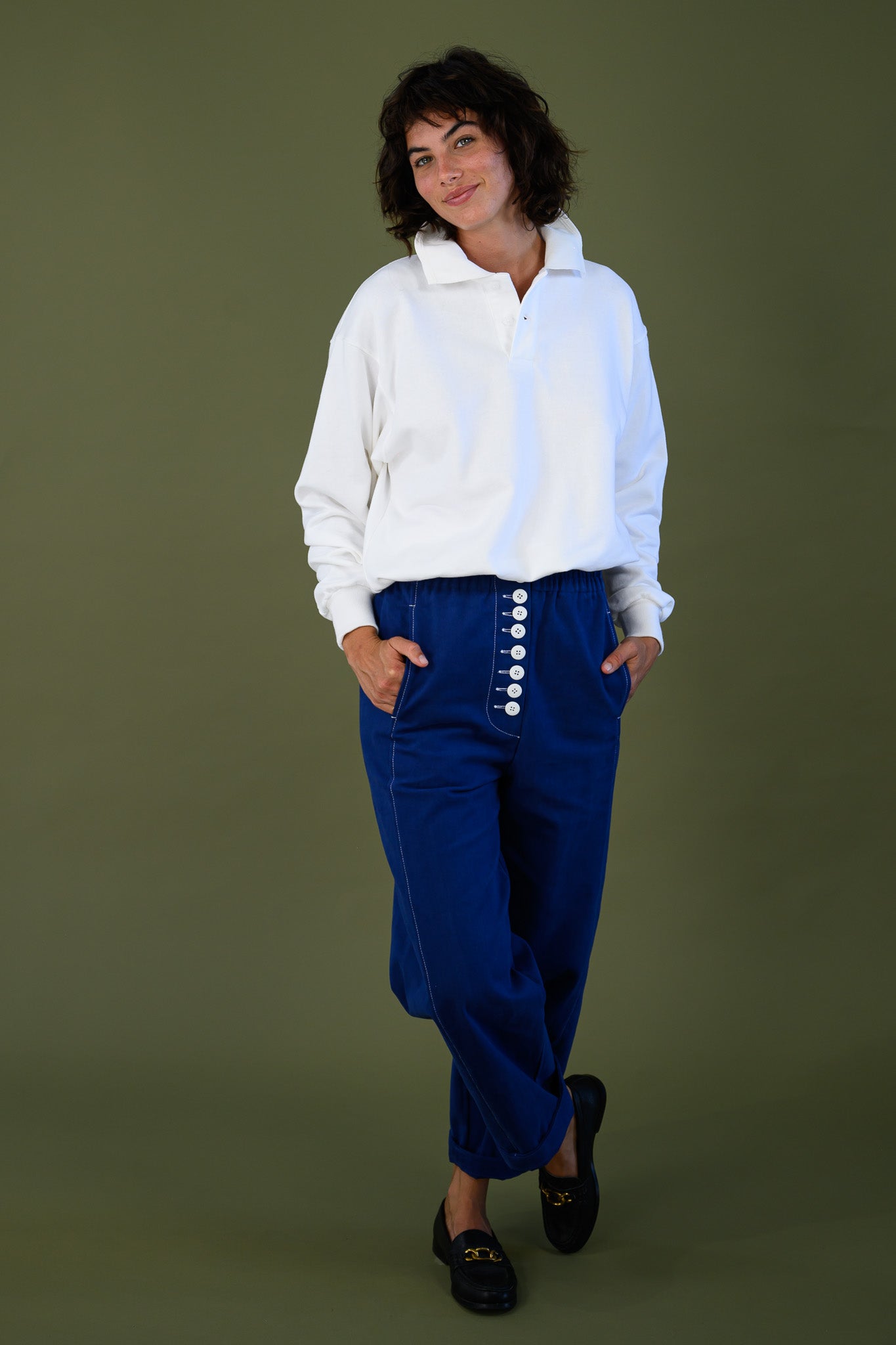 French navy cotton twill button pants styled with relaxed white shirt showing front button detail and tapered leg fit