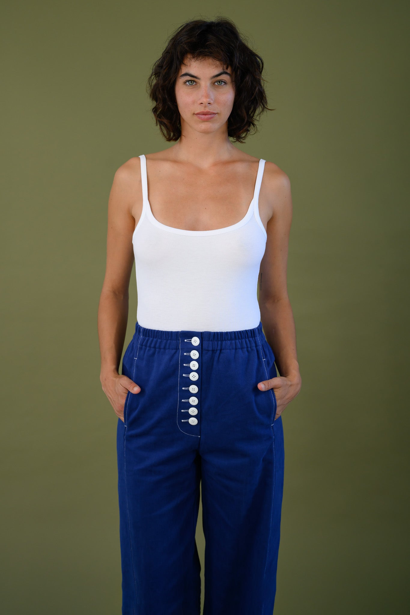 Front view of French navy cotton twill button pants styled with white tank top