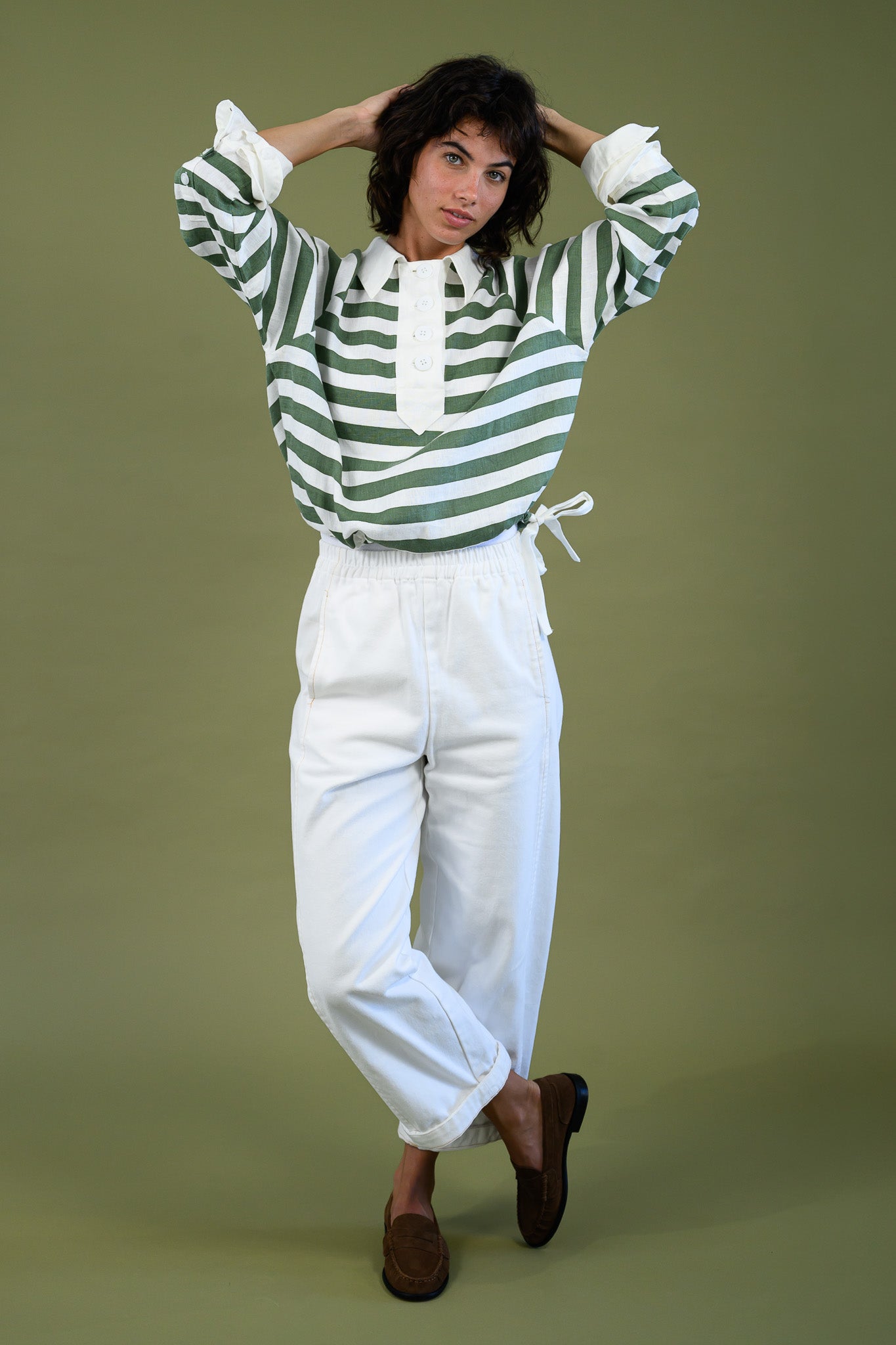Model wearing harrington rugby shirt in linen with hands over her head show the fit.