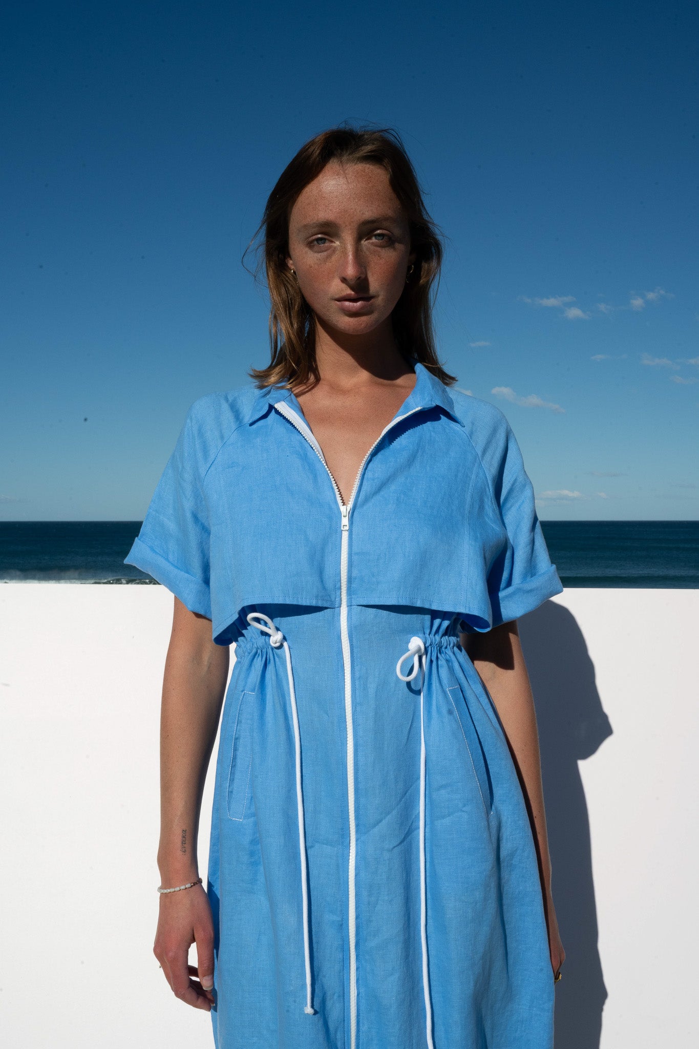 The Boy and I Iconica Dress in blue with white contrast zip and drawstring waist, front view.