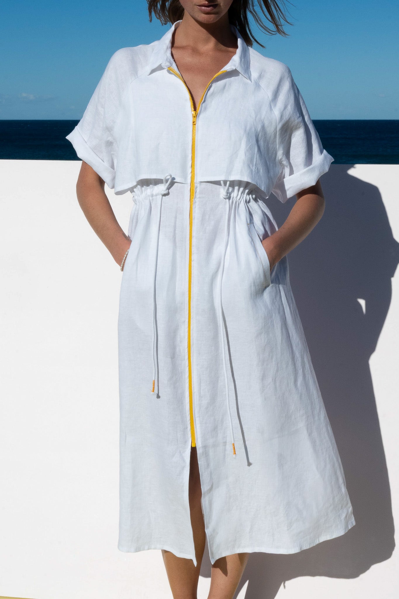 White Iconica Dress with yellow zip – relaxed styling with hands in pockets