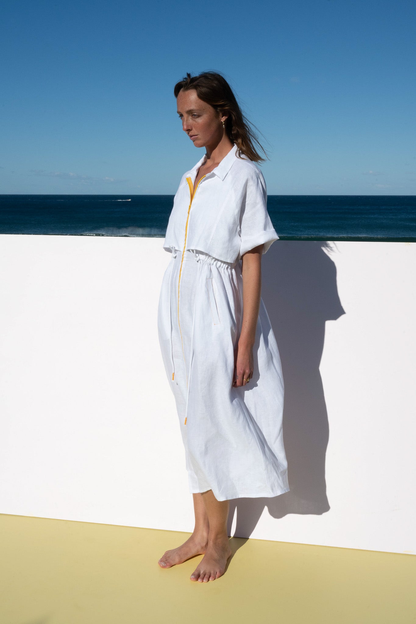 White Iconica Dress with yellow zip – angled front pose highlighting overlay and bold yellow zipper