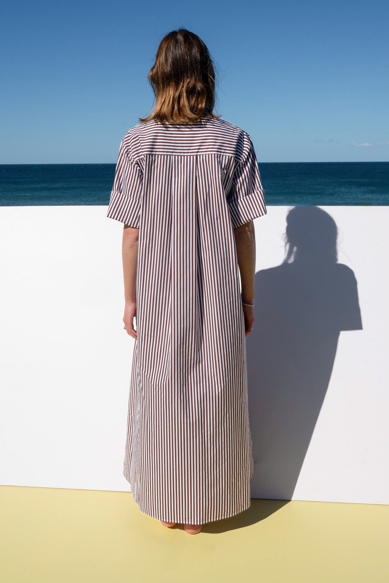 Back view of The Boy & I Leon Dress in espresso stripe highlighting vertical stripes and flowing silhouette.