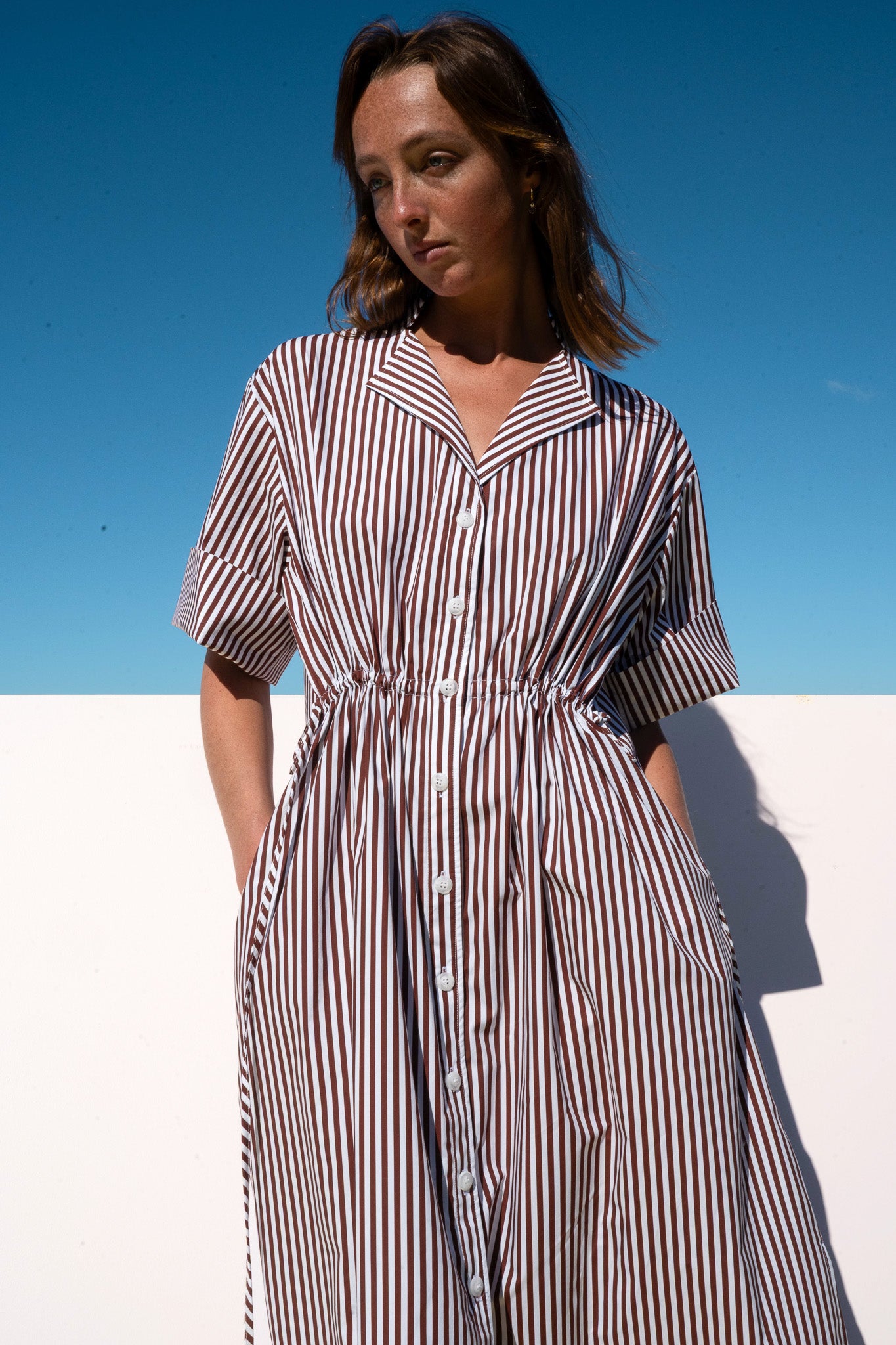 Model wearing The Boy & I Leon Dress in espresso stripe with button-down front and relaxed fit.