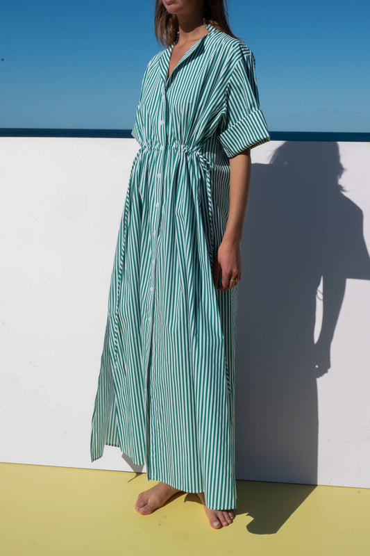 Model wearing The Boy & I Leon Dress in lush green meadow stripe cotton, showing front detail with drawstring waist and rolled sleeve.