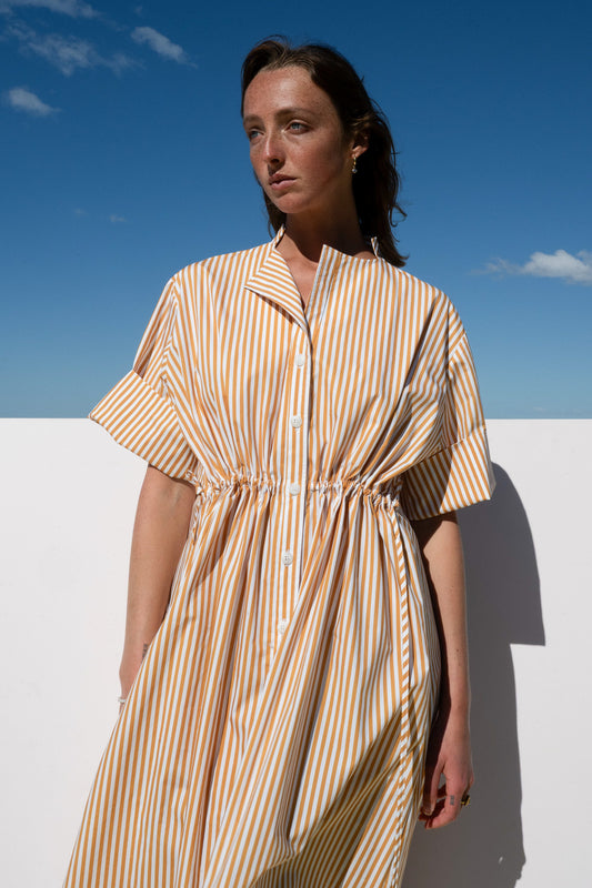 Front close-up of the Leon Dress in marigold stripe cotton featuring buttons and gathered waist.