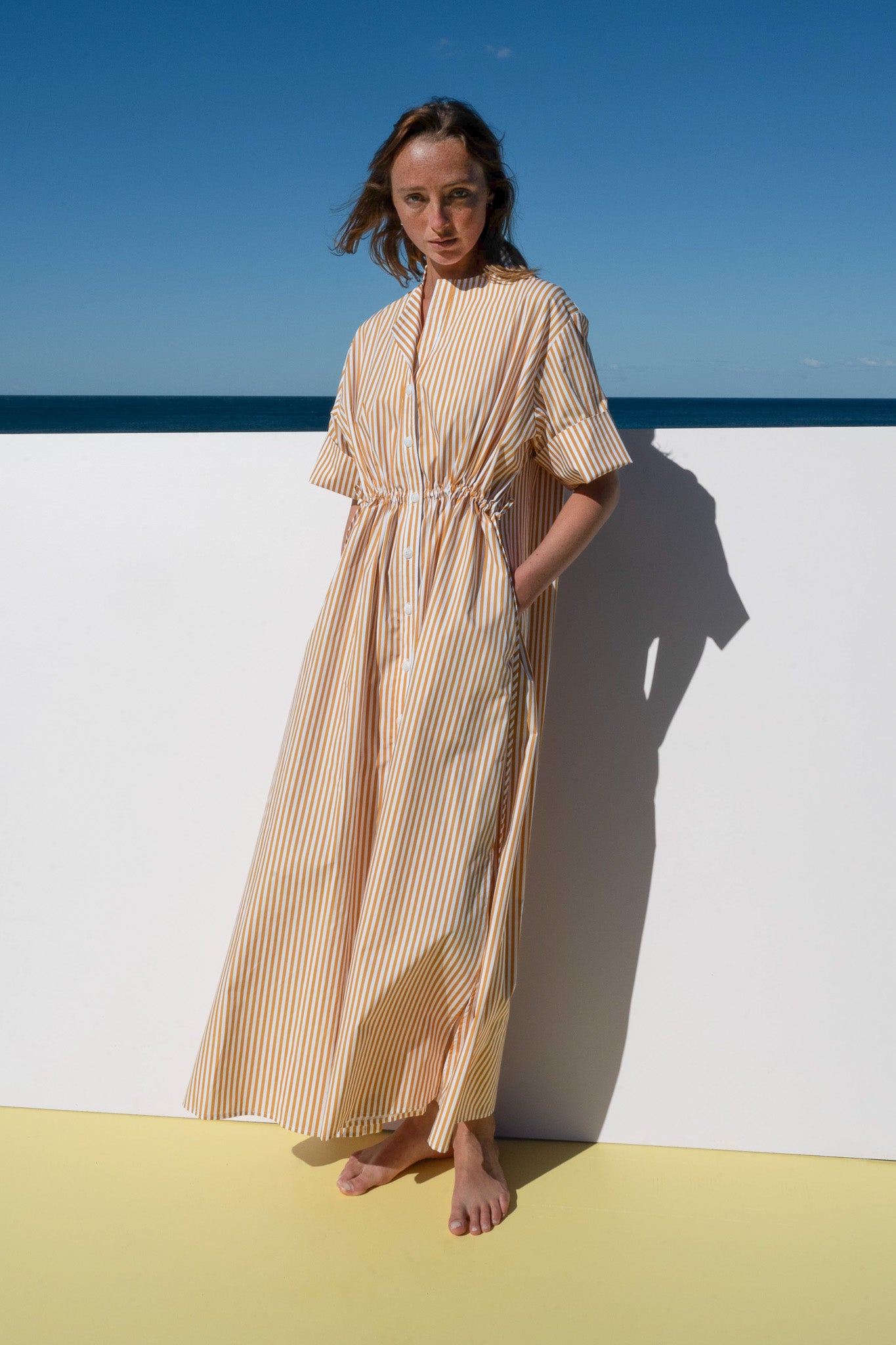 Full-length view of the Leon Dress in marigold stripe cotton with button-down front and relaxed fit.