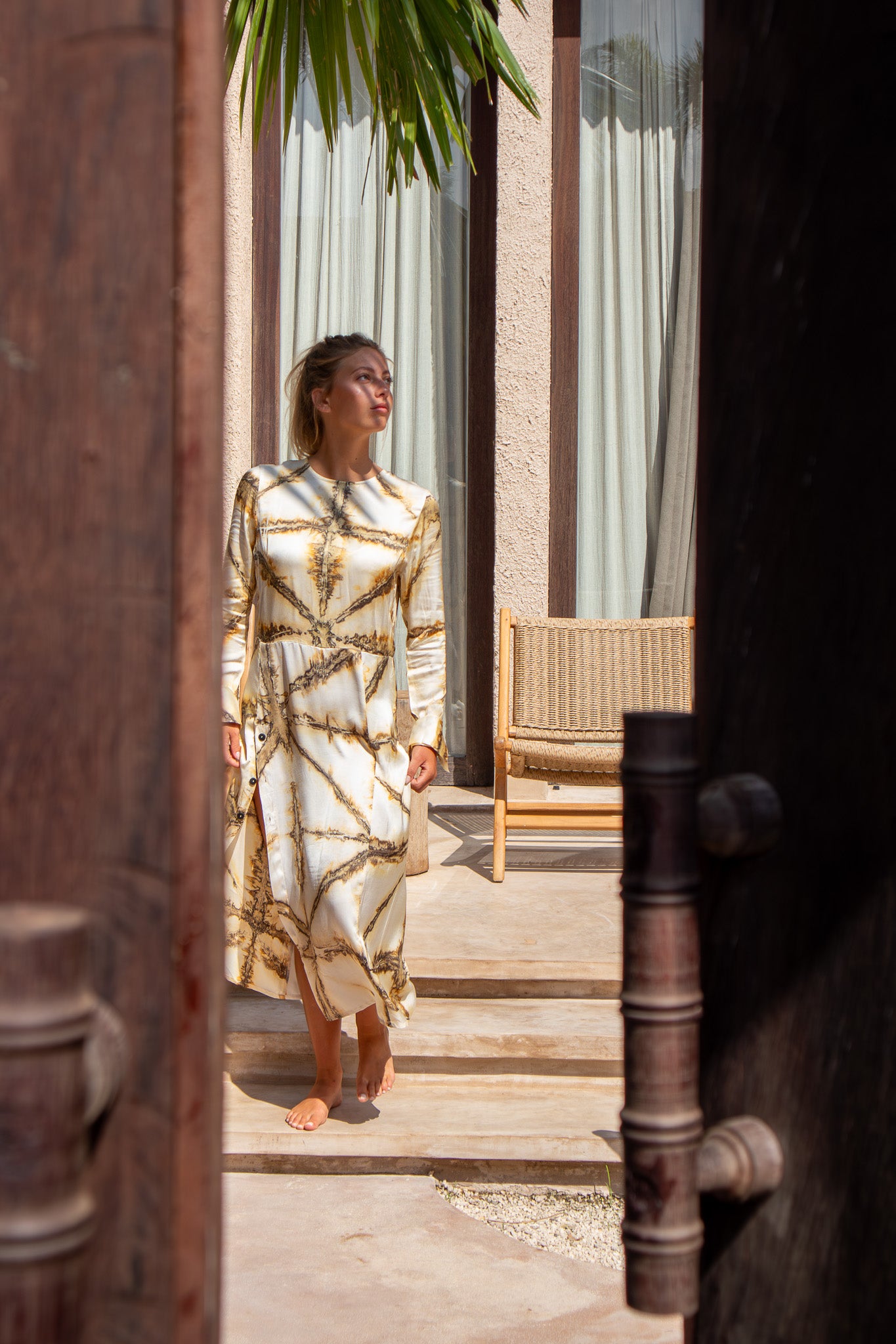 Maggie Dress in motion as model walks through arched doorway wearing Earth Shibori tie-dye print from The Boy and I