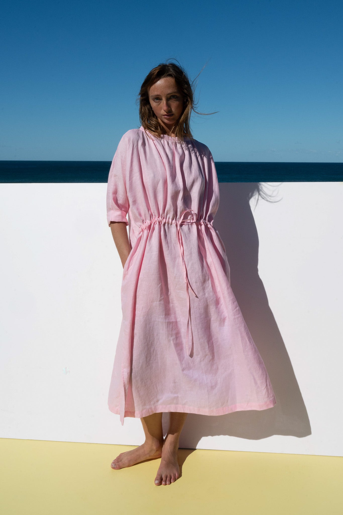 The Moments Dress in Bonbon Pink shown from a front angle, relaxed fit with side pockets.