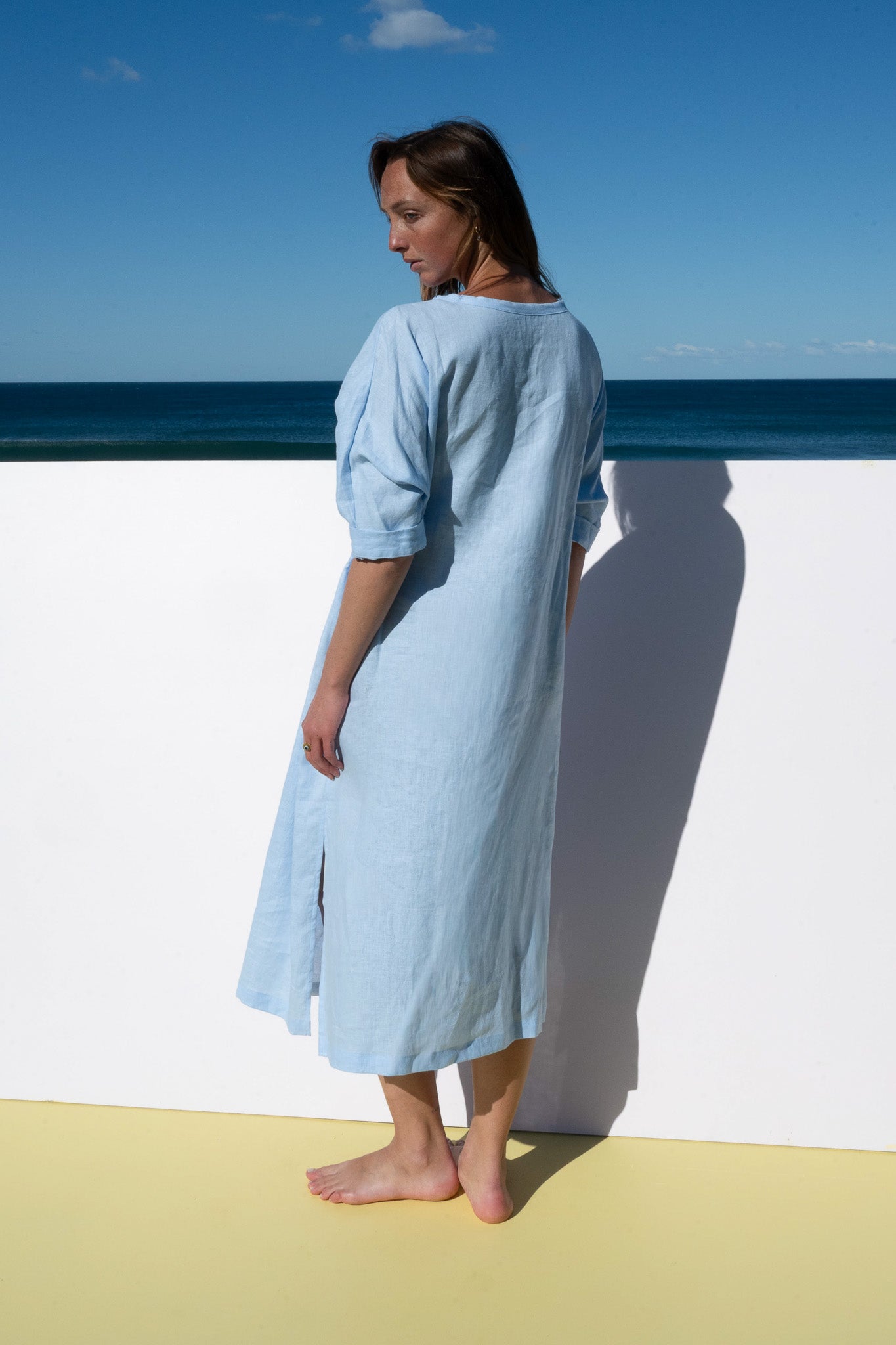 Back view of The Moments Dress in corn flour blue linen, showing clean lines and soft silhouette.