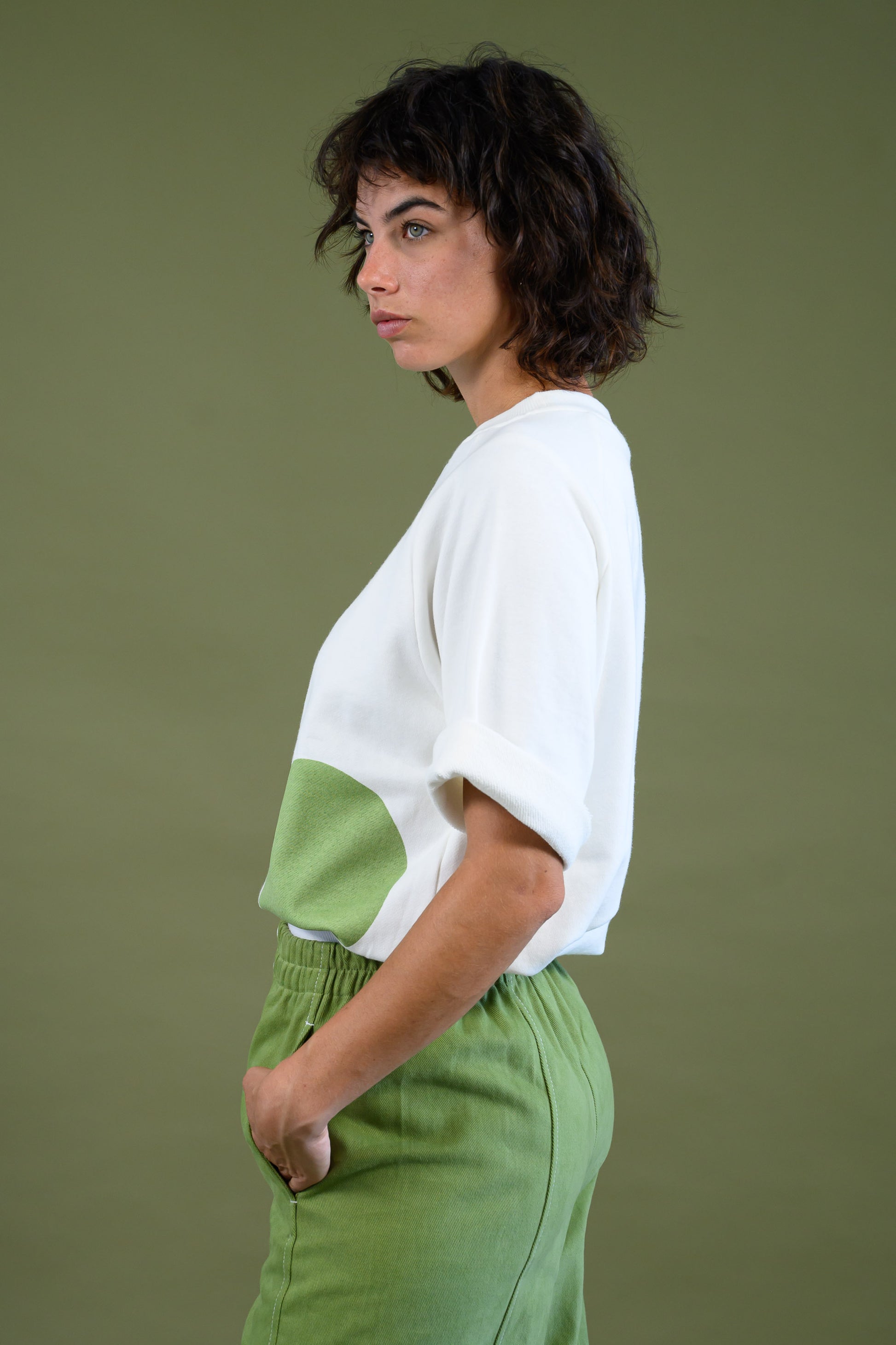 Side profile of raglan sleeve cotton sweatshirt with green dot detail styled with green pants