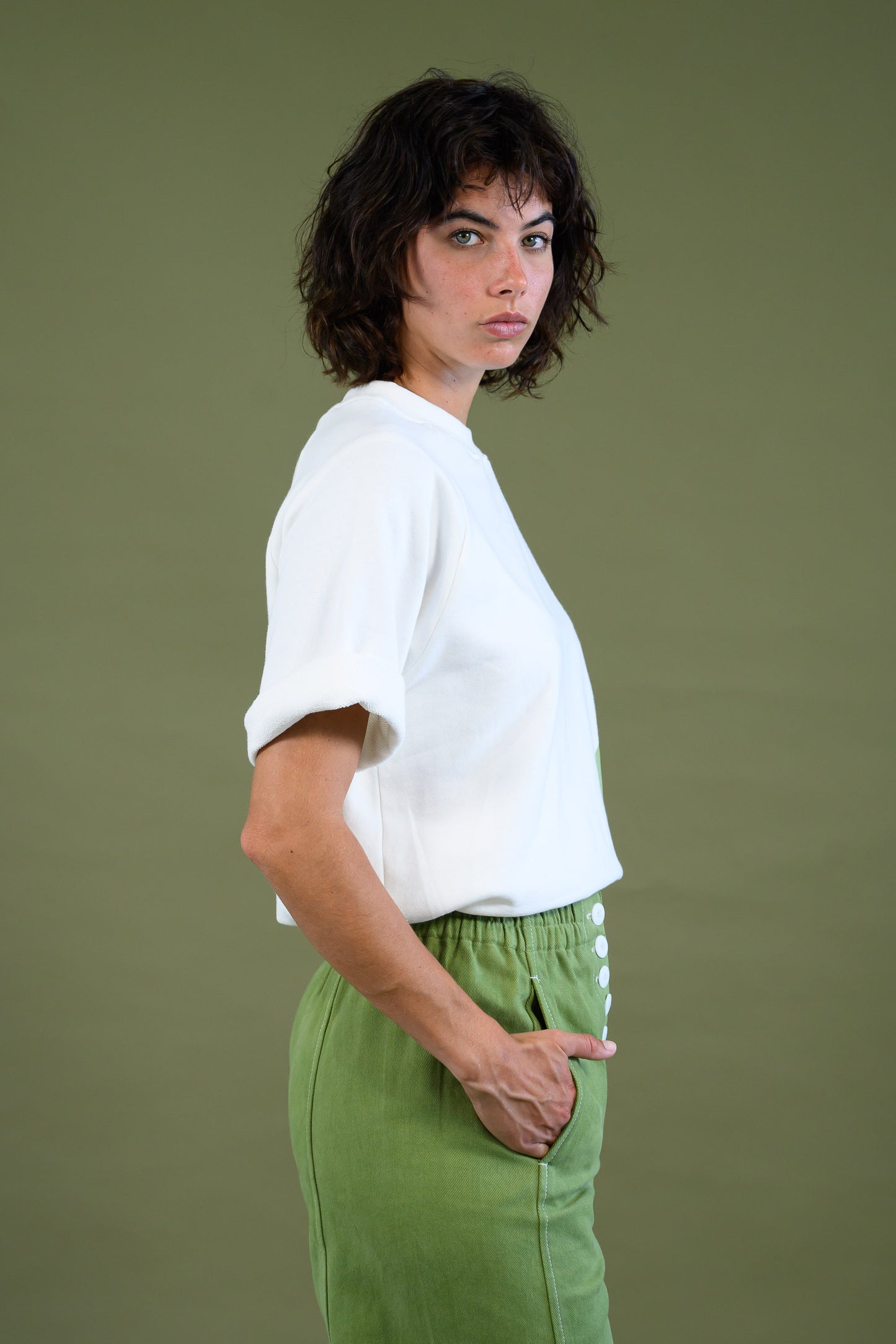 White raglan sleeve sweatshirt with model on the side and hands in her pockets 