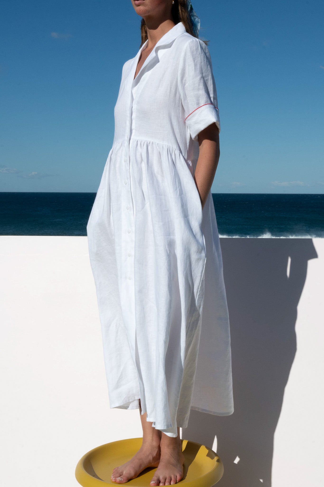 Side view of the Siena Dress in lightweight linen with short sleeves and red piping