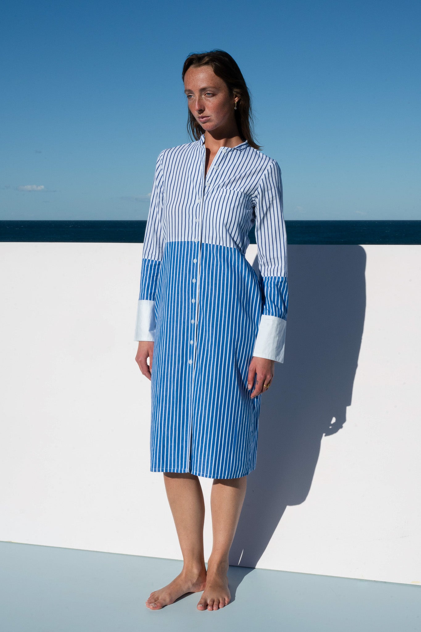 Model in the Sisto Dress in blue and white stripe, front view in natural sunlight