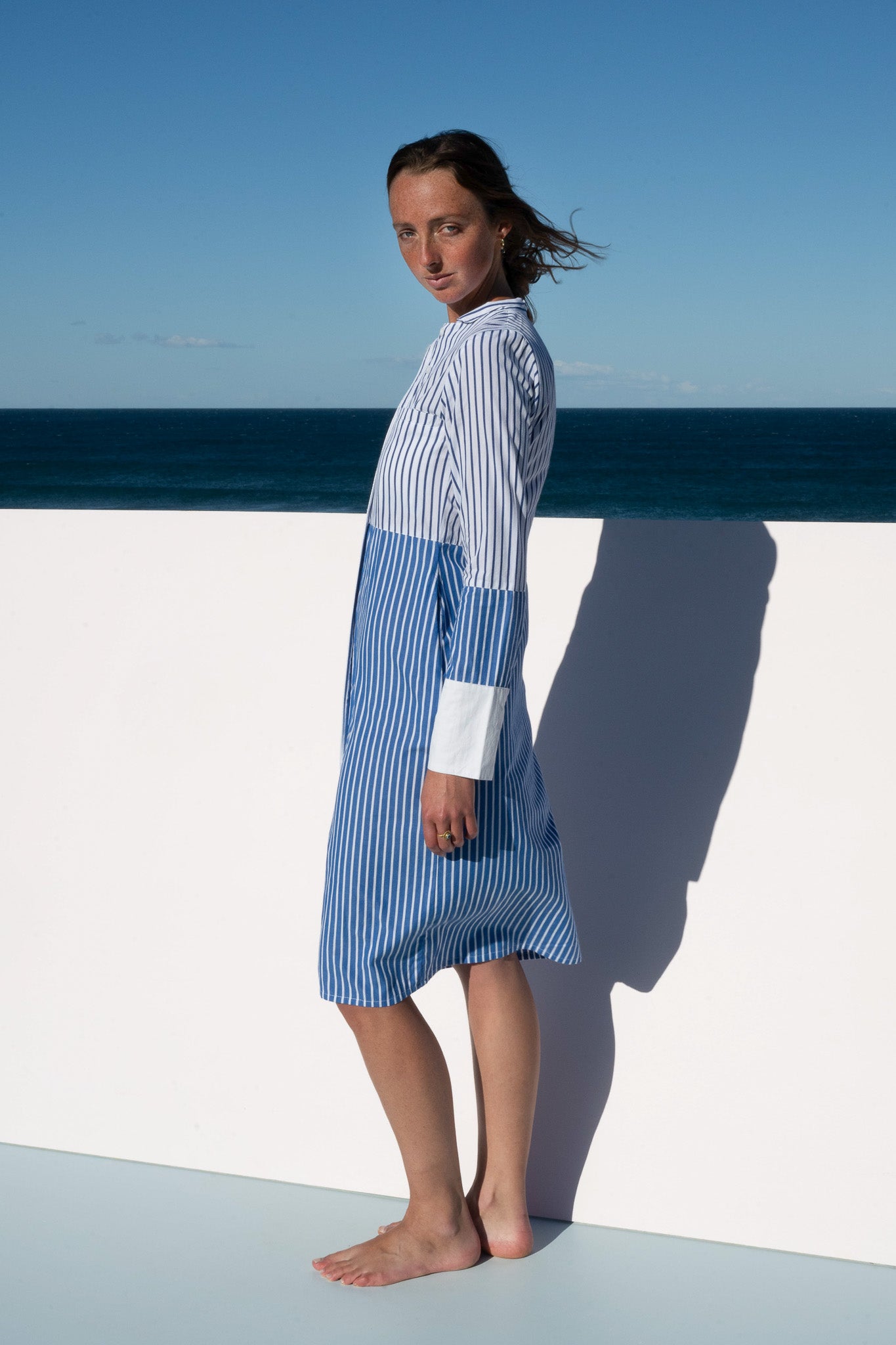Profile view of the Sisto Dress in blue and white stripe with long sleeves.