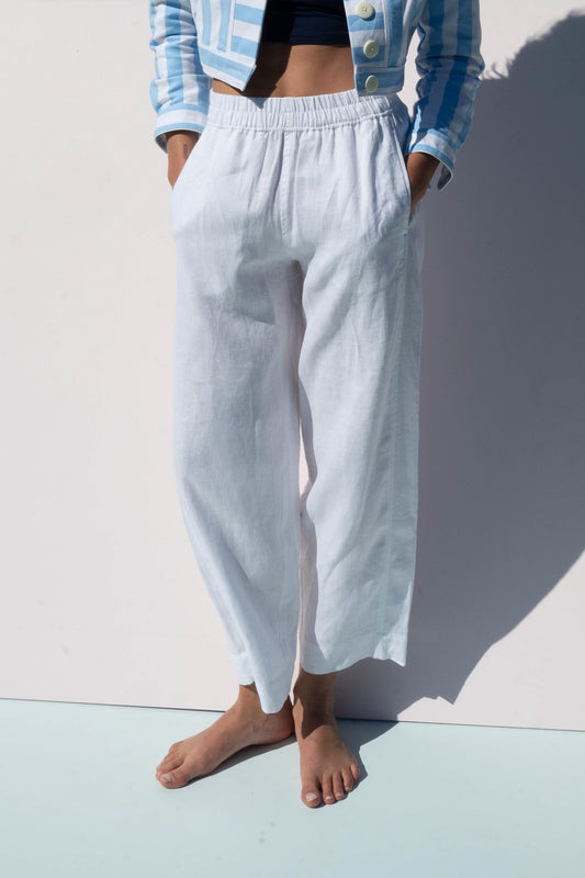 Close-up of Solero Pant in white linen, showing relaxed fit and pockets, paired with a blue striped cropped jacket.