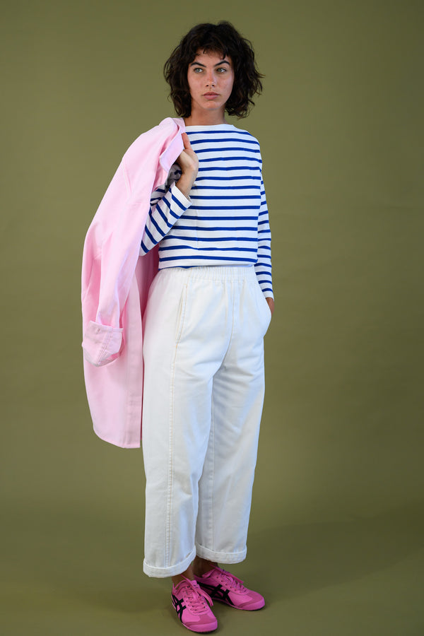 Blaze jogger in white organic cotton twill with a relaxed barrel leg fit styled with striped top holding pink overshirt