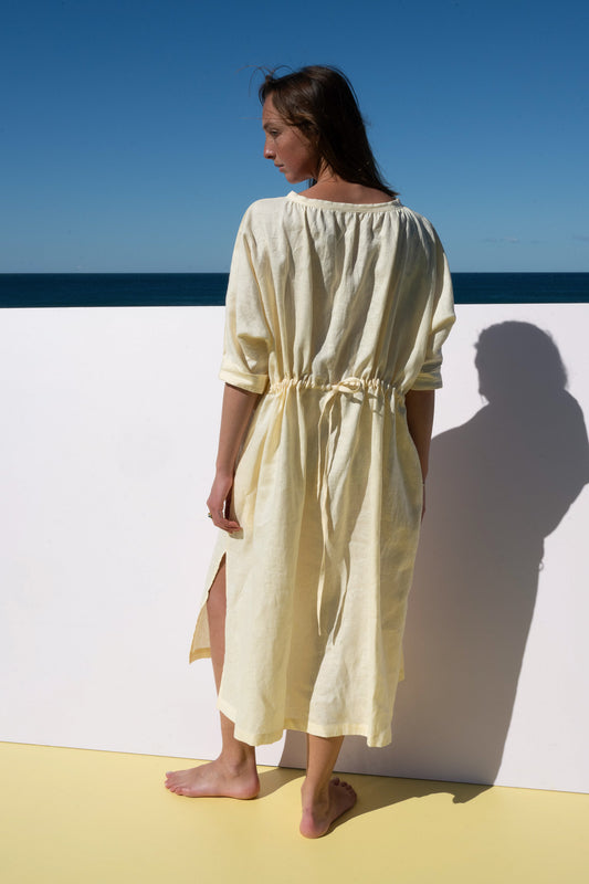 The Moments Dress in yellow linen – back view with adjustable tie waist and side slit detail