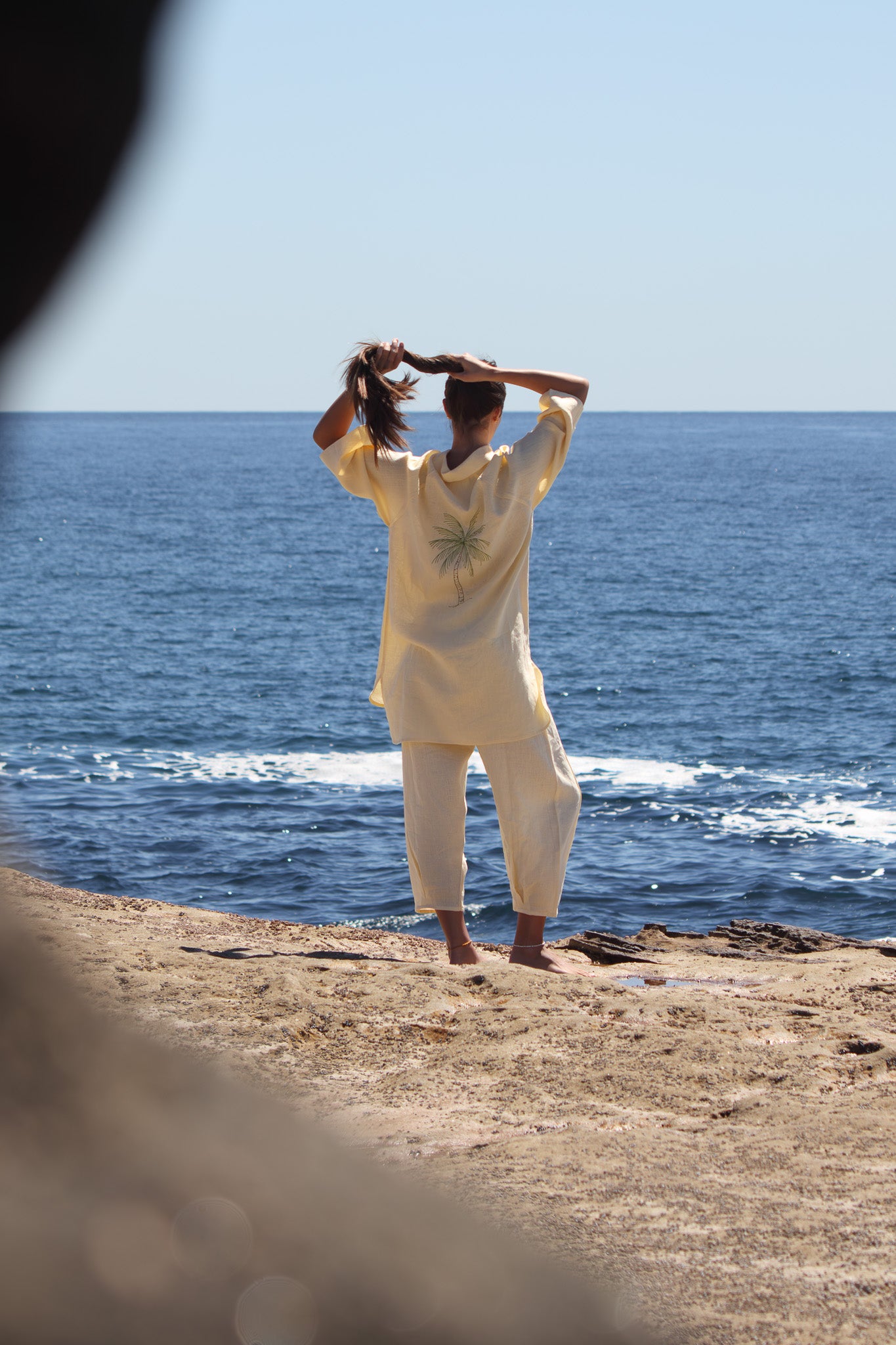Butter yellow Oceanic Shirt Dress with palm tree embroidery and soft linen drape by the ocean.