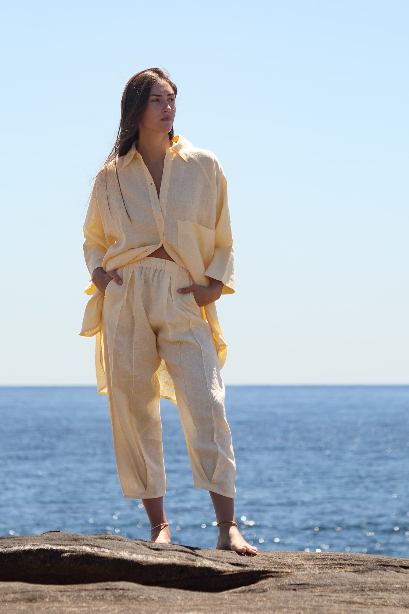 Butter yellow Oceanic Shirt Dress with palm tree embroidery worn open over relaxed linen pants.