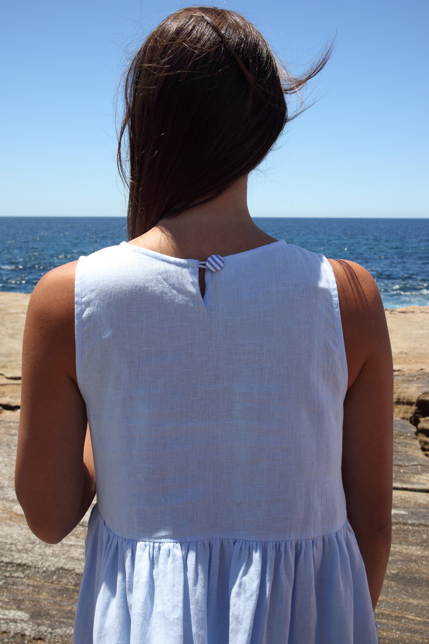 Back view of the Wonka Dress in sky blue linen, showing the striped covered button at the neckline.