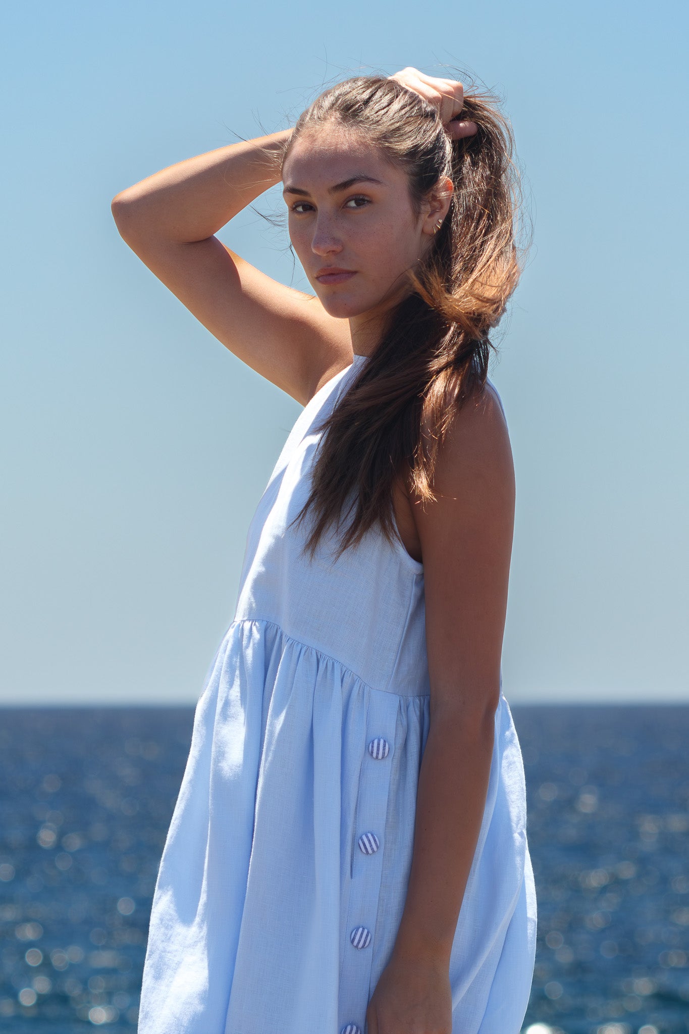 Side portrait of the Wonka Dress in sky blue linen, showing the striped covered buttons and soft gathers under the bust.