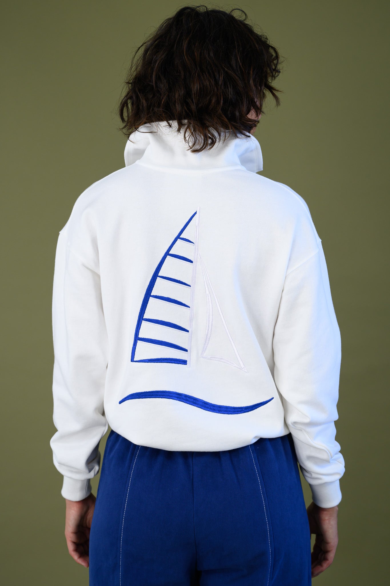 Back view of white cotton jumper highlighting blue embroidered sailboat detail