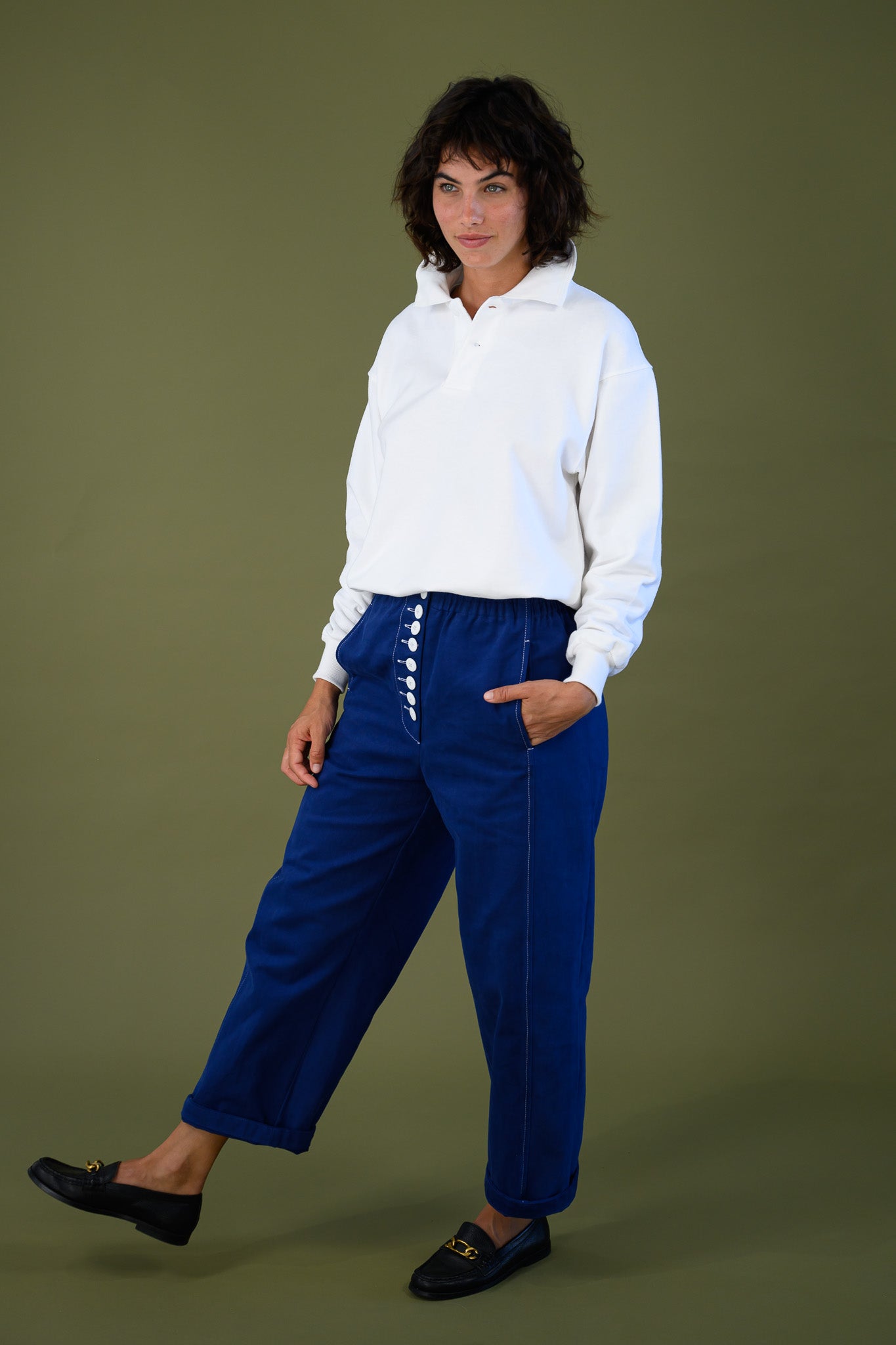 White cotton jumper styled with blue pants shown full body in movement