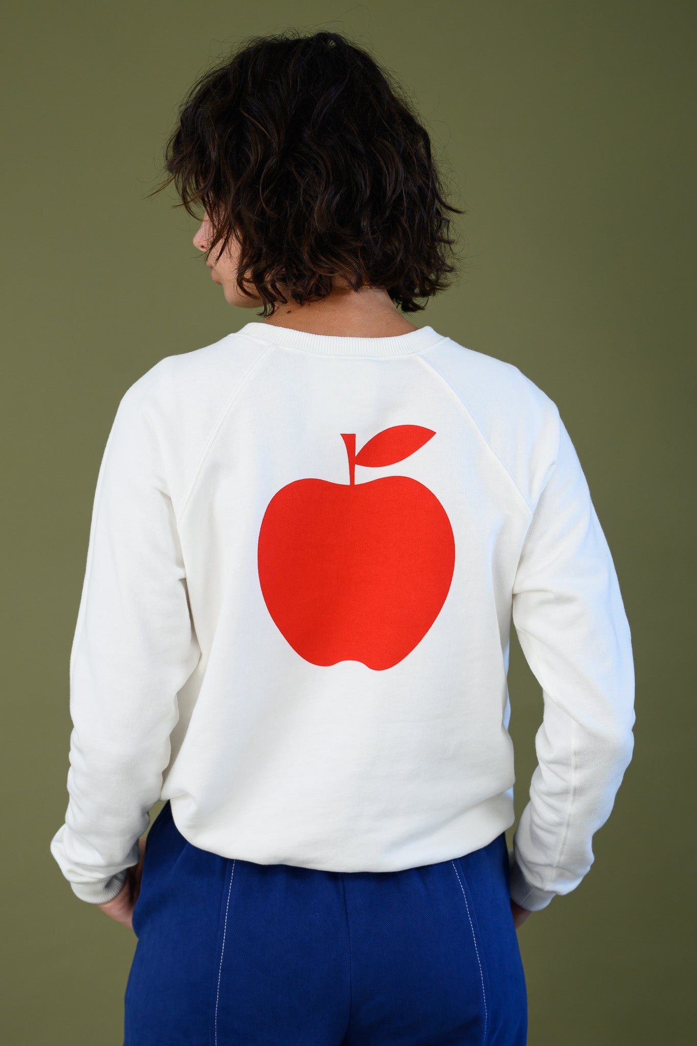 Close up of red apple print on back of white cotton sweatshirt