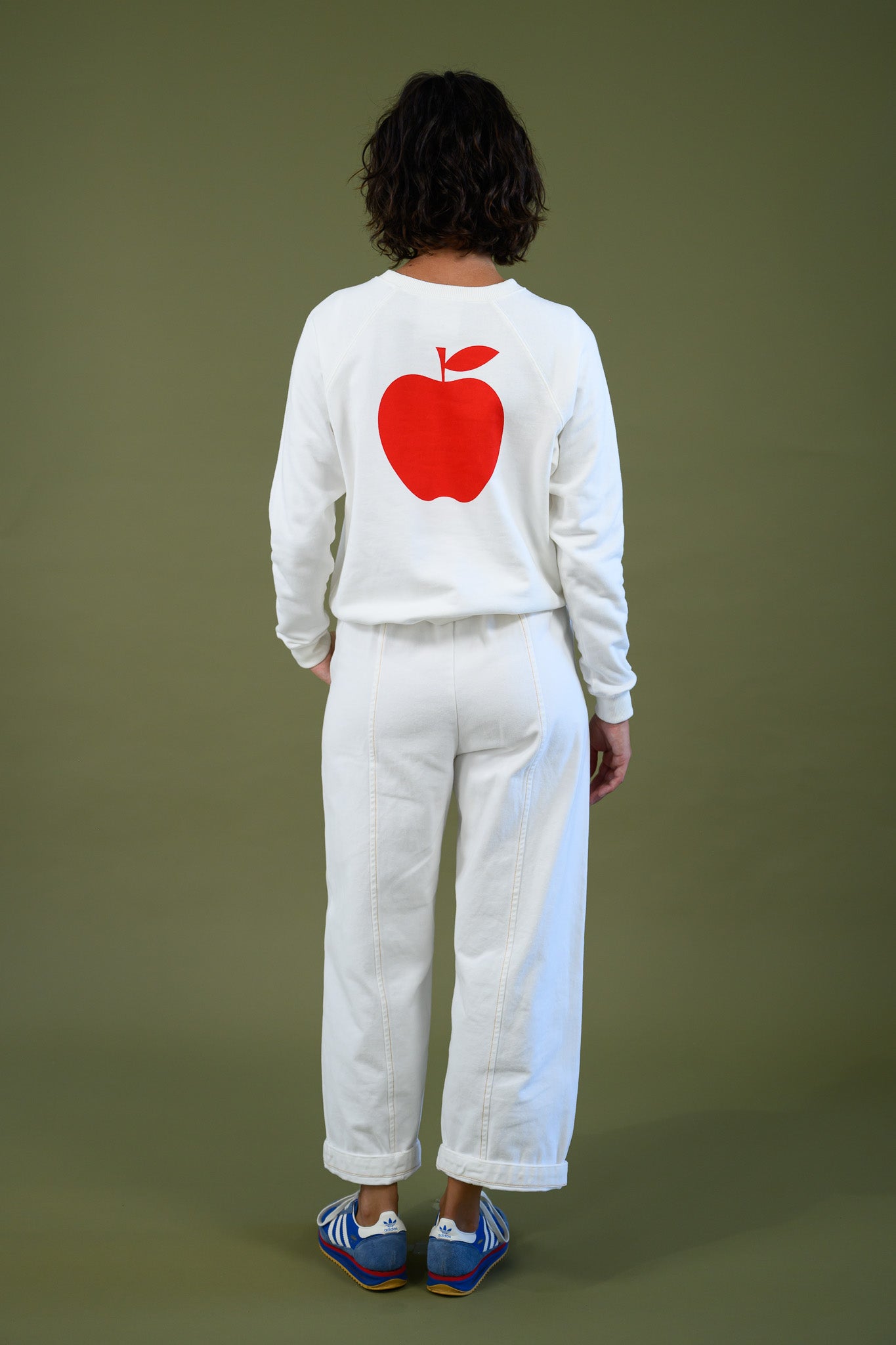 Back view of white cotton sweatshirt with large red apple print shown full length