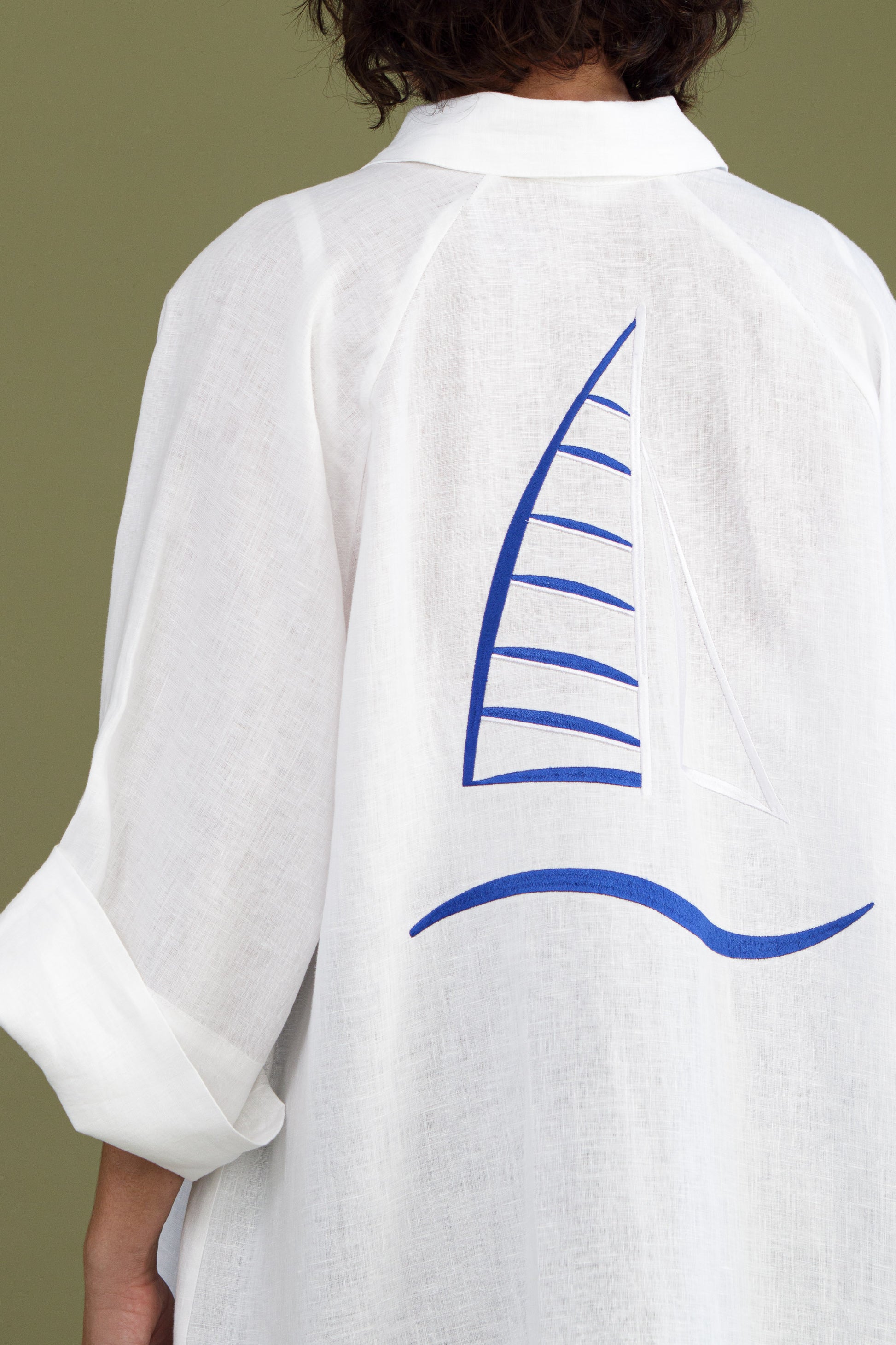Back view of white linen shirt dress with blue embroidered sailboat detail