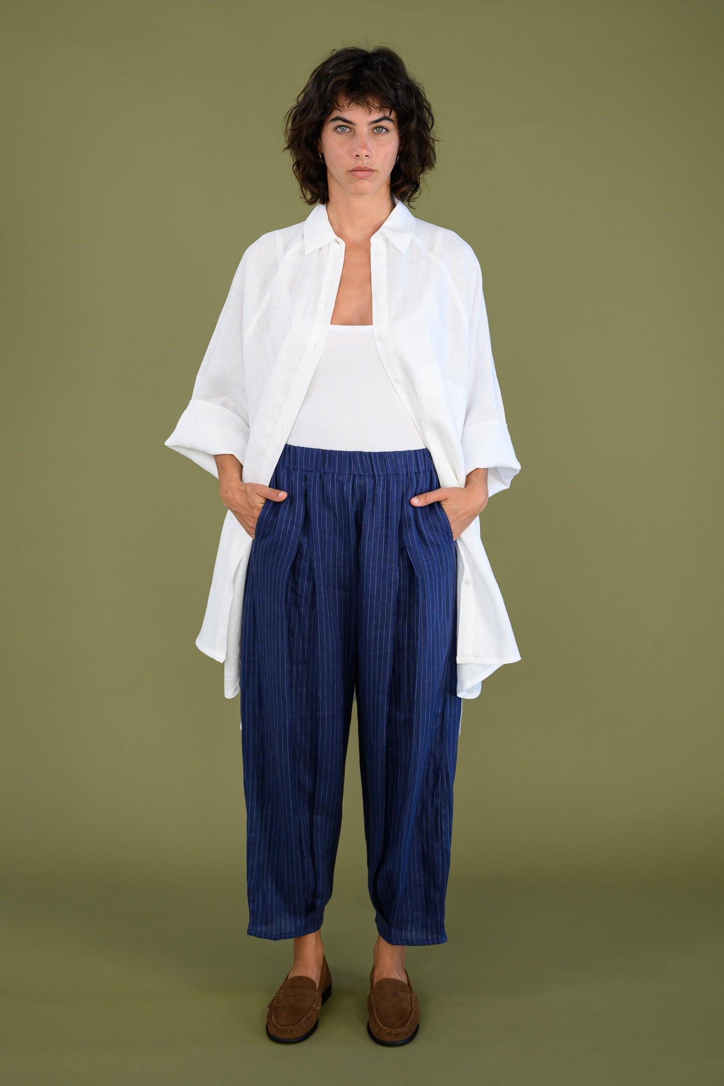 White linen shirt dress styled with blue pants shown full length on model